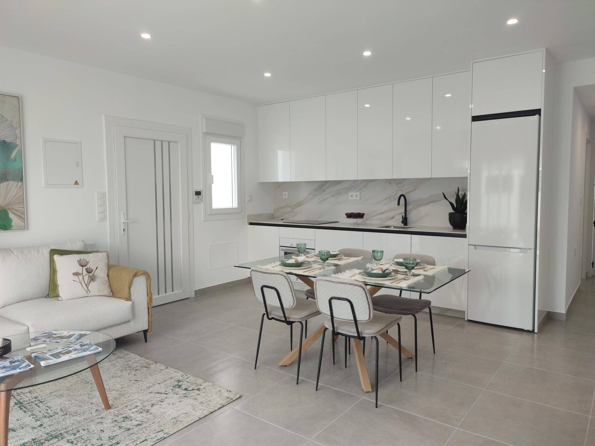Moderne offene Küche mit weißen Hochglanzfronten, integriertem Kühlschrank und Essbereich.