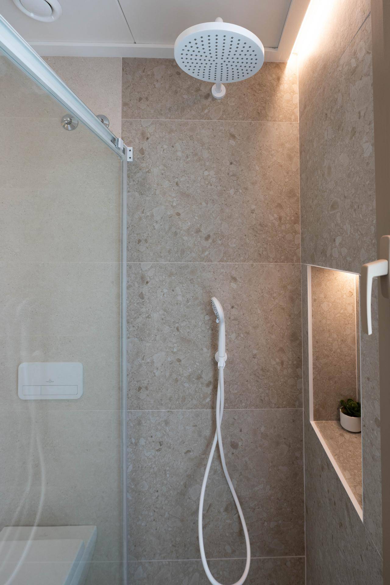 Moderne Dusche mit Regenduschkopf, Nische für Utensilien und Fenster für Tageslicht.