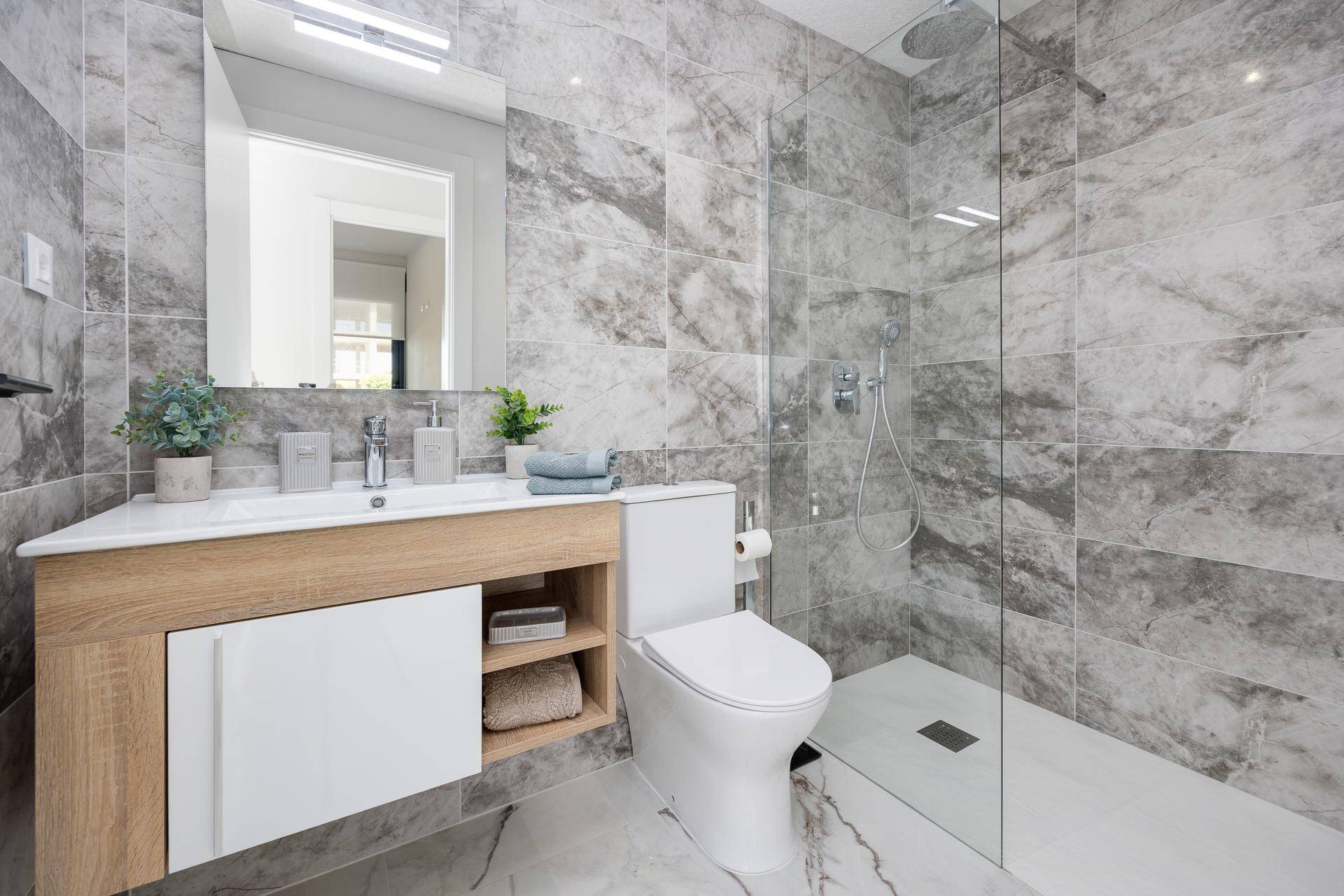 Modernes Badezimmer mit begehbarer Dusche, Marmorfliesen und elegantem Waschtisch.