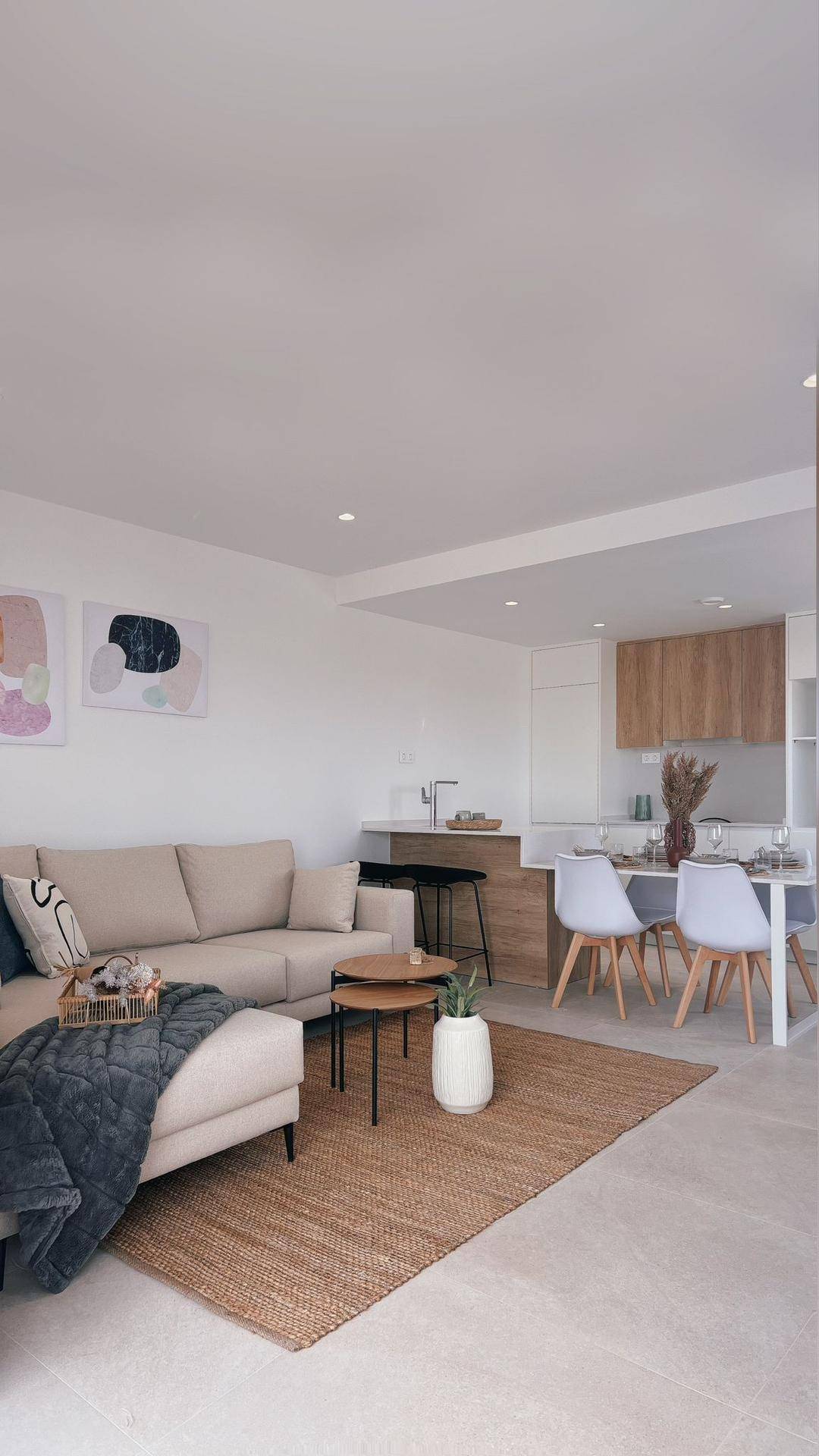 Offener Wohn- und Essbereich mit integrierter Küche, modernem Sofa und Teppichboden.