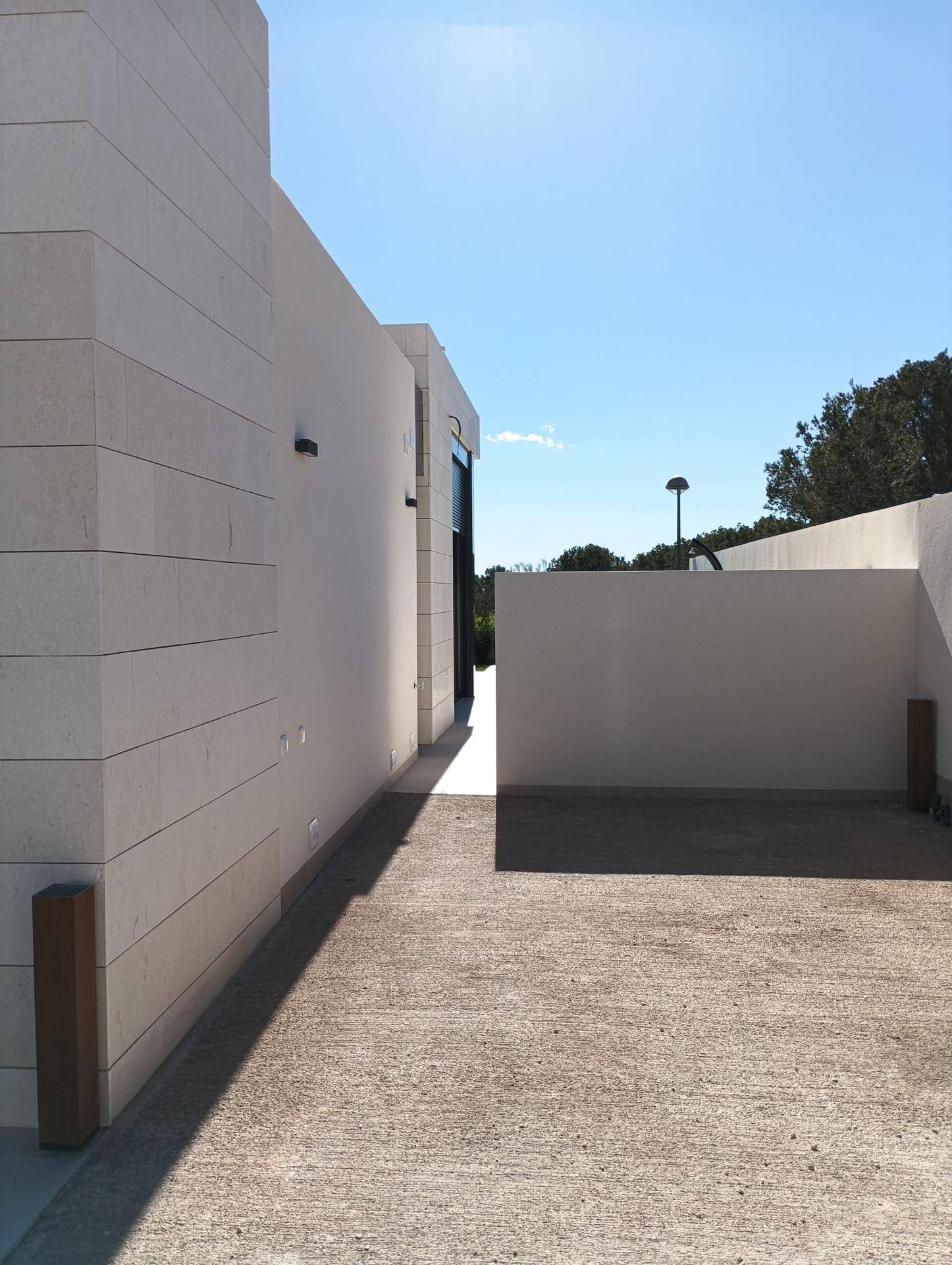 Geräumiger gepflasterter Zugangsbereich neben der modernen Villa mit klaren Linien und viel Sonnenlicht.