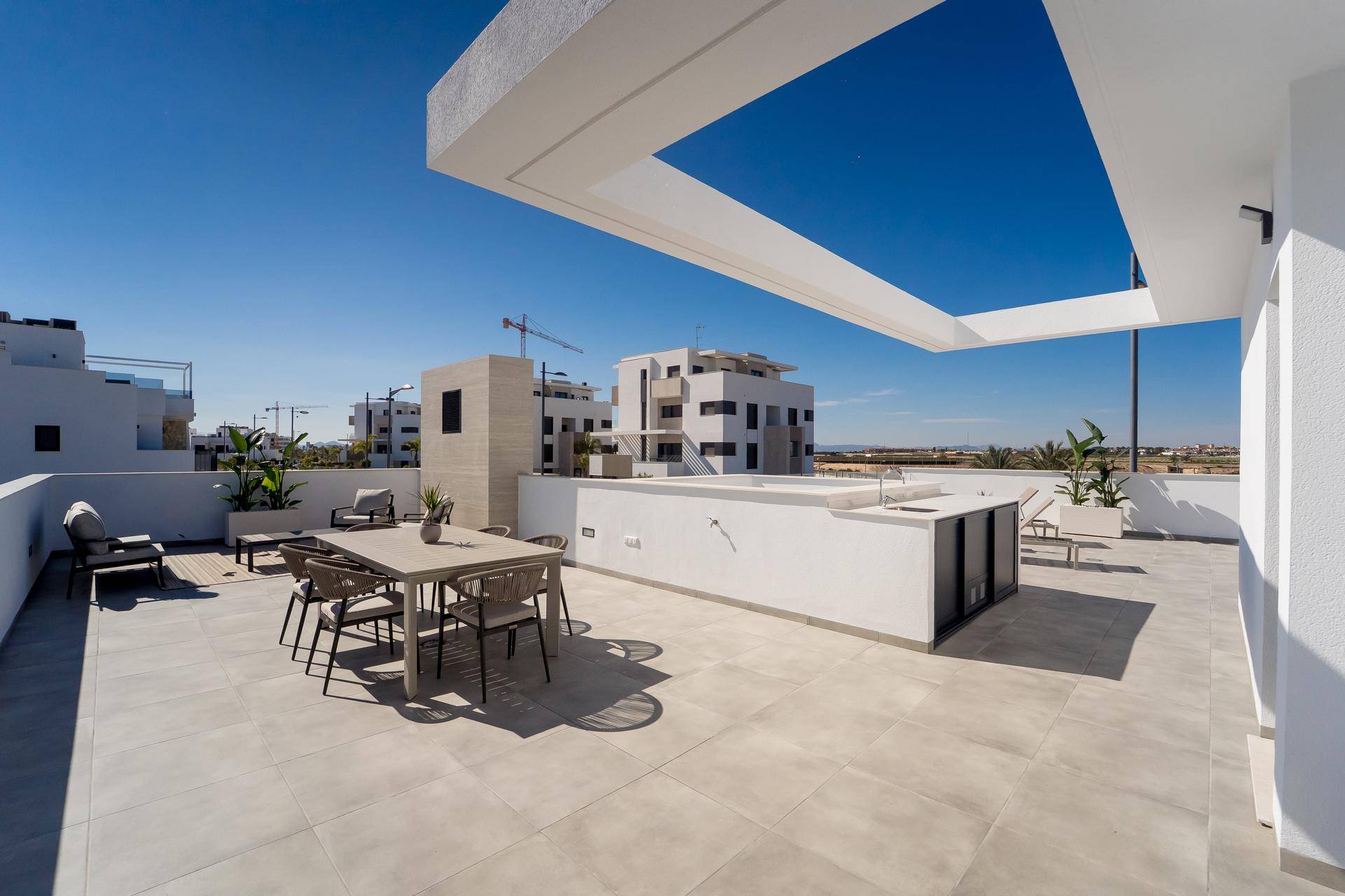Geräumige Dachterrasse mit Essbereich, Sonnenliegen und Blick auf die Umgebung.