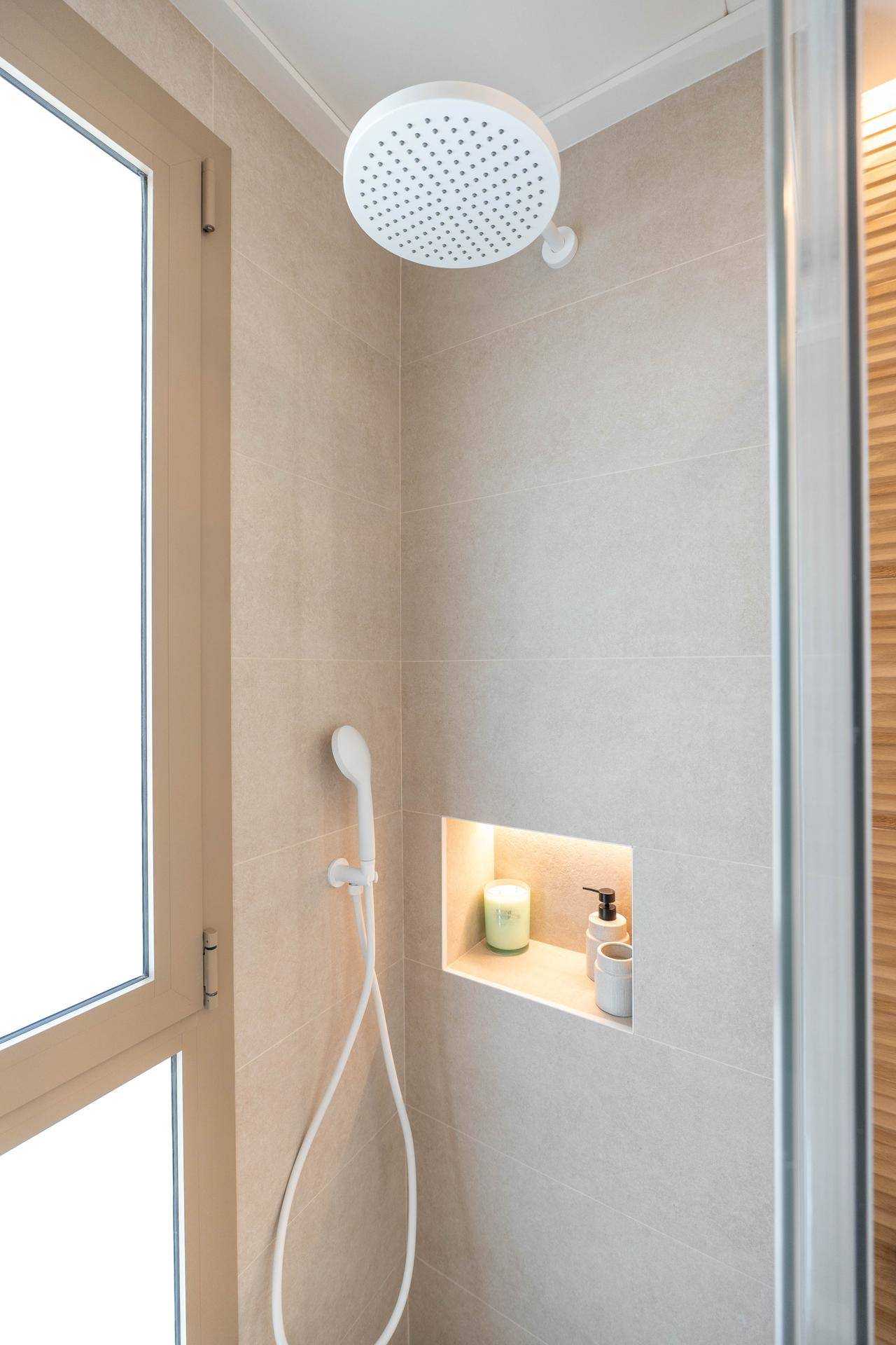 Moderne Dusche mit Regenduschkopf, Nische für Utensilien und Fenster für Tageslicht.