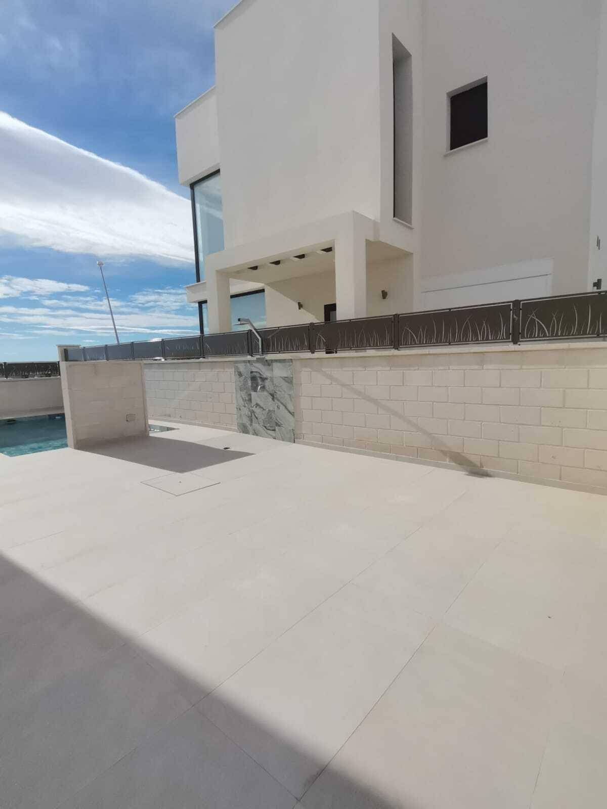 Moderne Gebäudeseite mit Poolbereich und minimalistischer Gestaltung unter blauem Himmel.