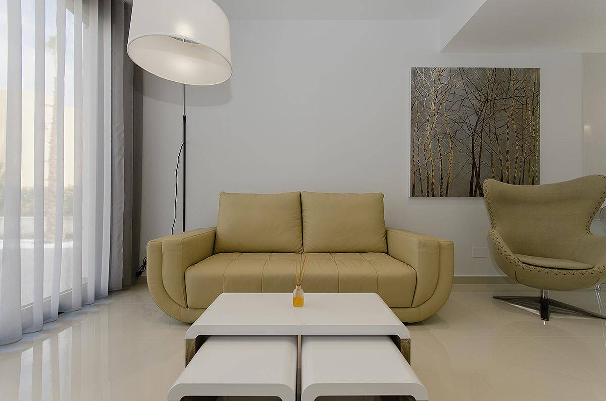Modernes Wohnzimmer mit beigem Sofa, elegantem Sessel und großem Fenster.