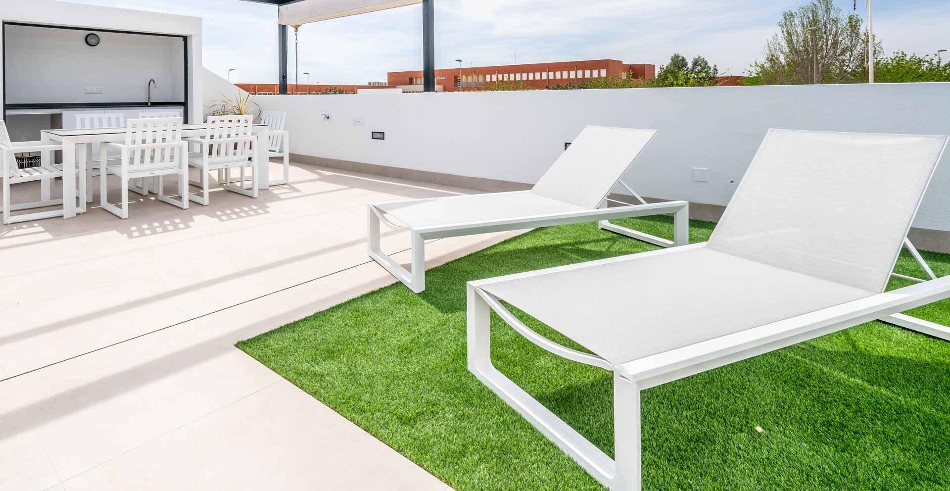 Geräumige Dachterrasse mit Liegestühlen und Kunstrasen für entspannte Stunden.