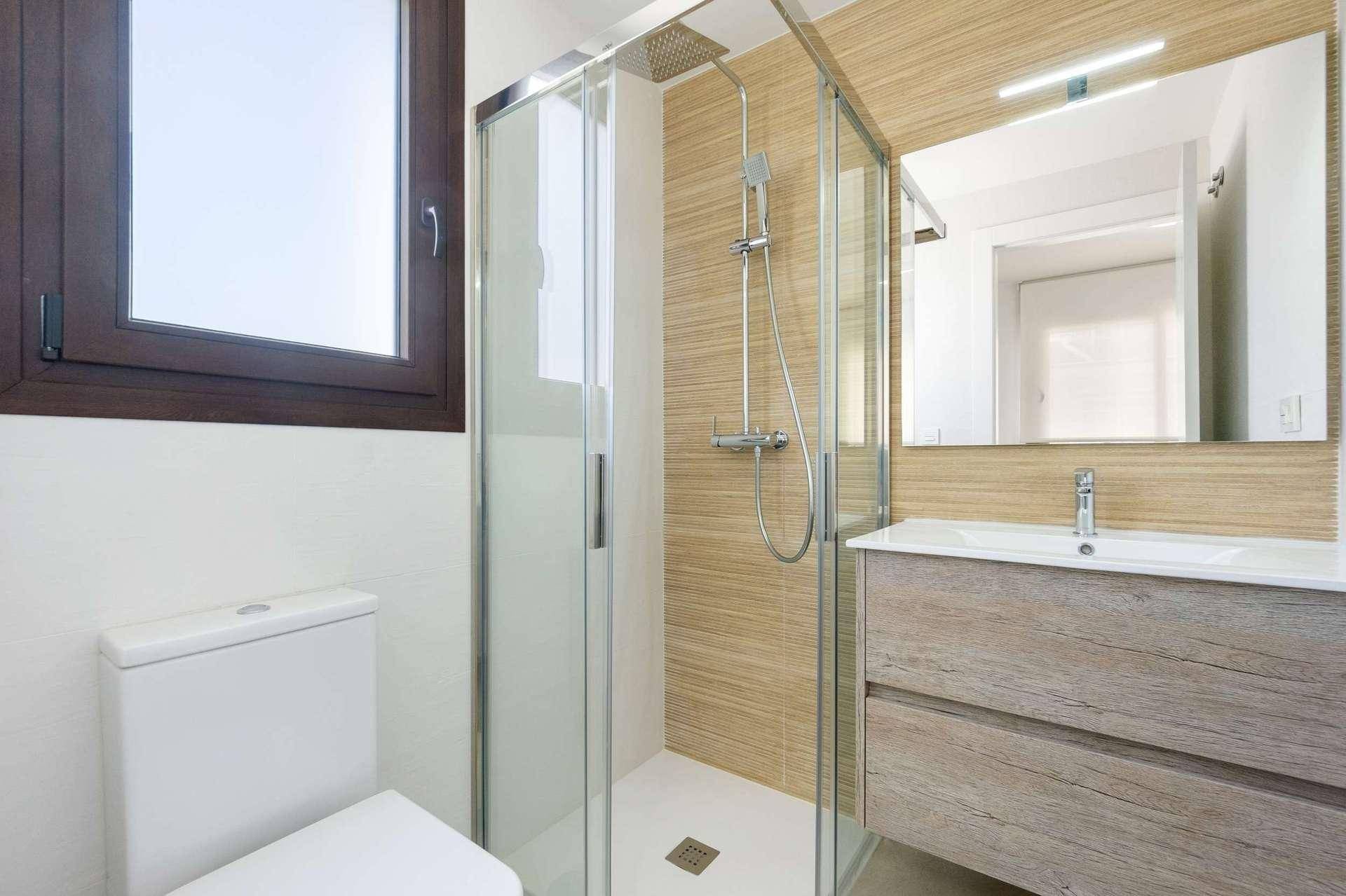 Modernes Badezimmer mit Duschkabine, WC, Holzoptik-Waschtisch und Fenster für Tageslicht.