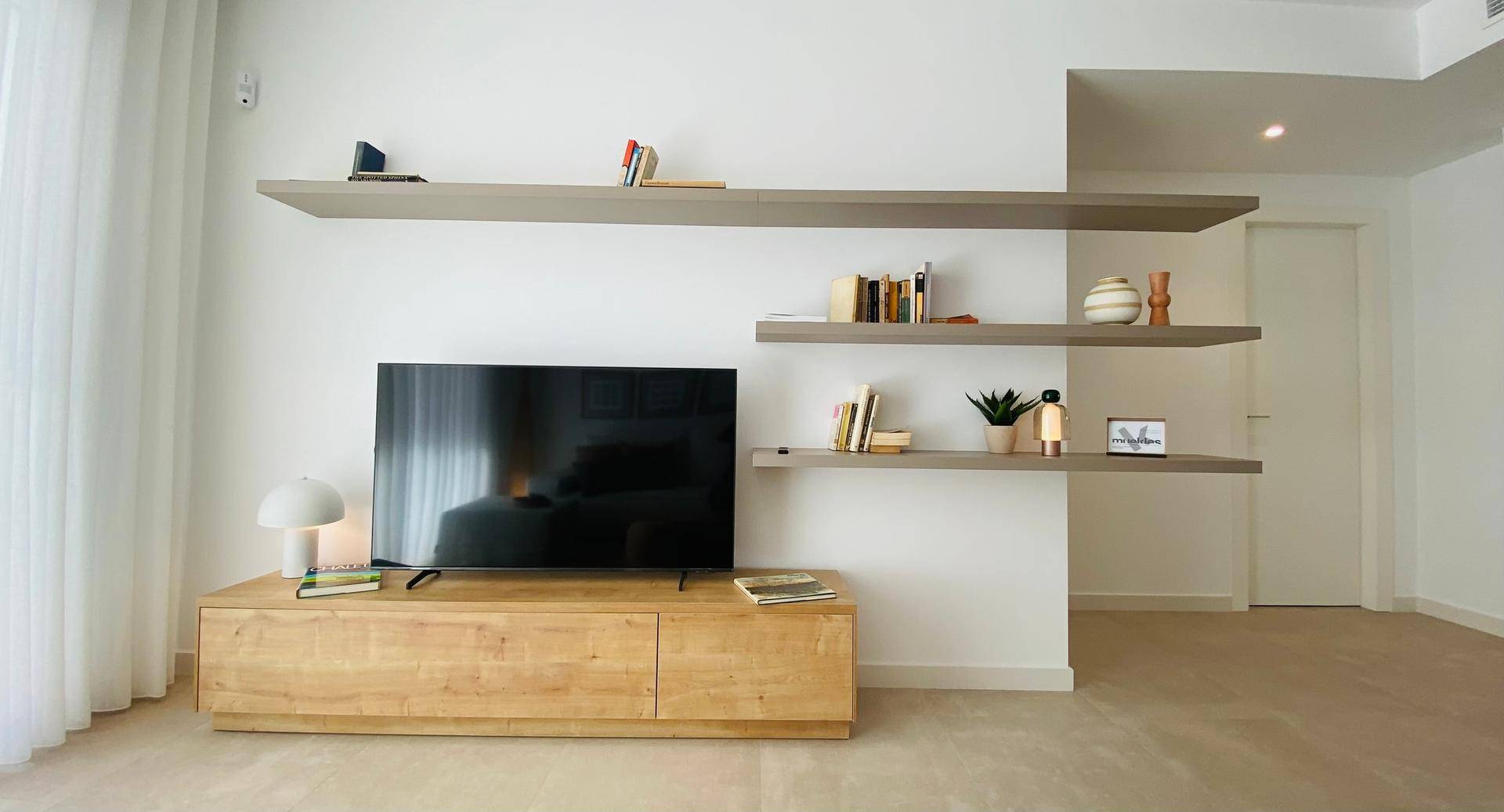 Wohnzimmer mit modernem TV-Möbel, schwebenden Regalen und minimalistischer Dekoration.