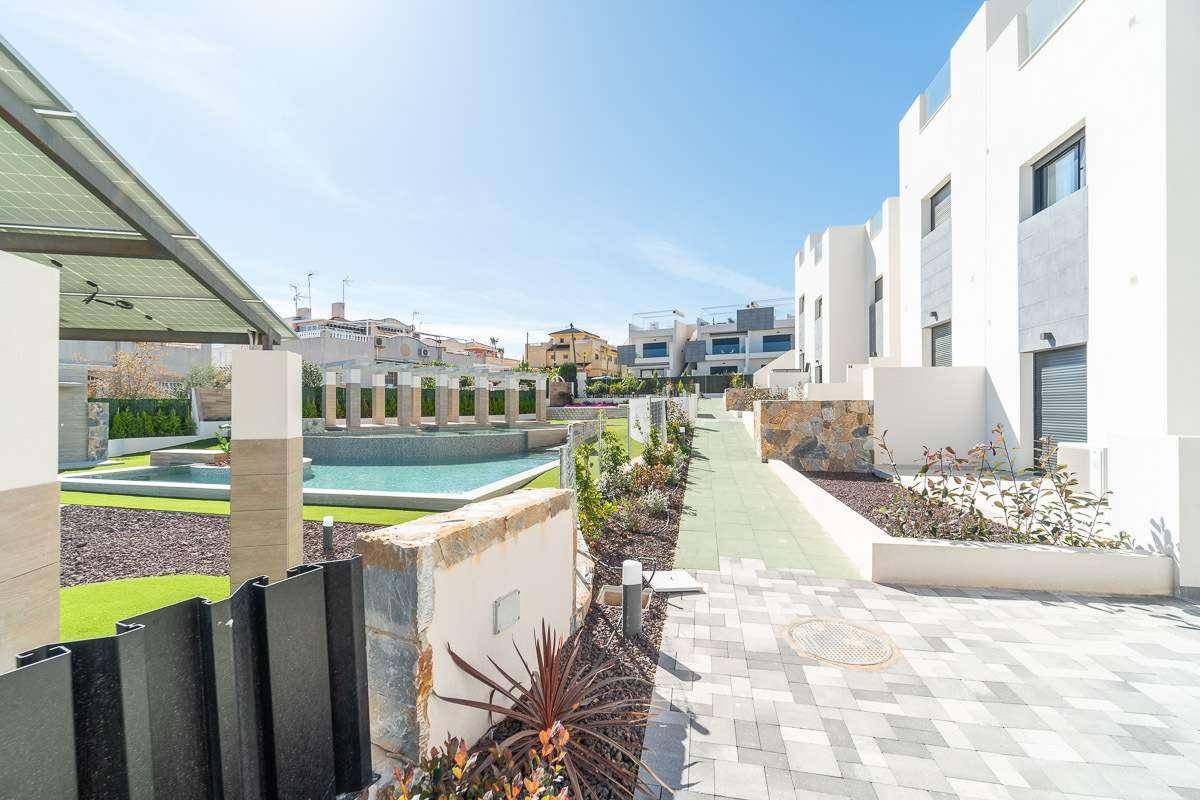 Gemeinschaftsgarten mit Poolbereich, gepflegten Grünflächen und modernen Gebäuden im Hintergrund.