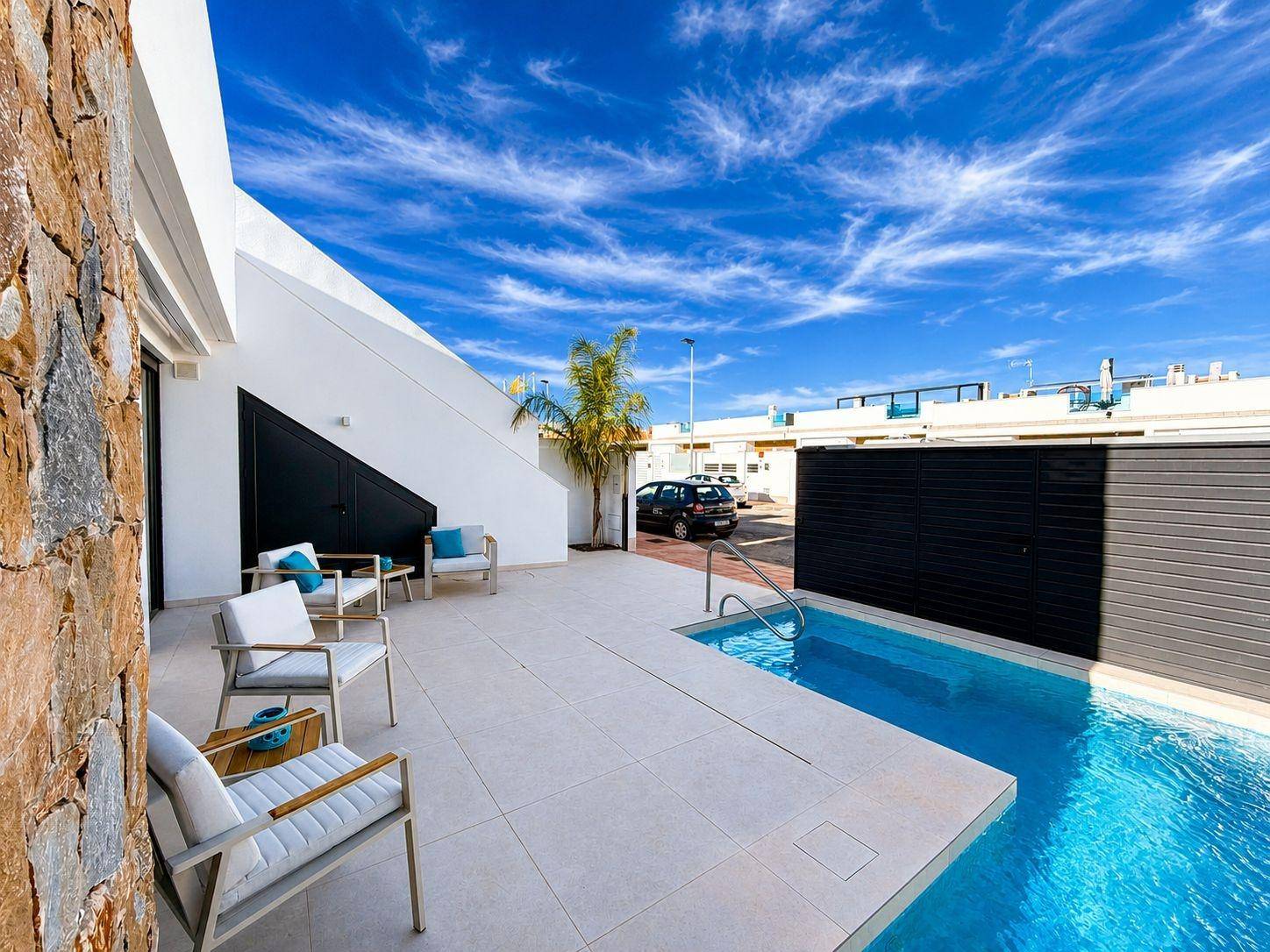 Geräumige Terrasse mit Pool, Loungemöbeln und Zugang zum Haus, umgeben von Steinmauern.