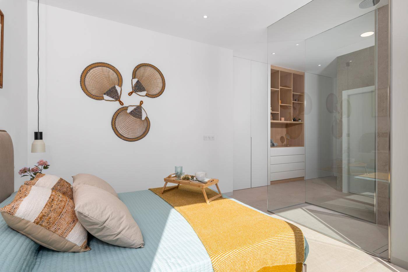 Helles Schlafzimmer mit Doppelbett und offener Glasdusche, modern eingerichtet.