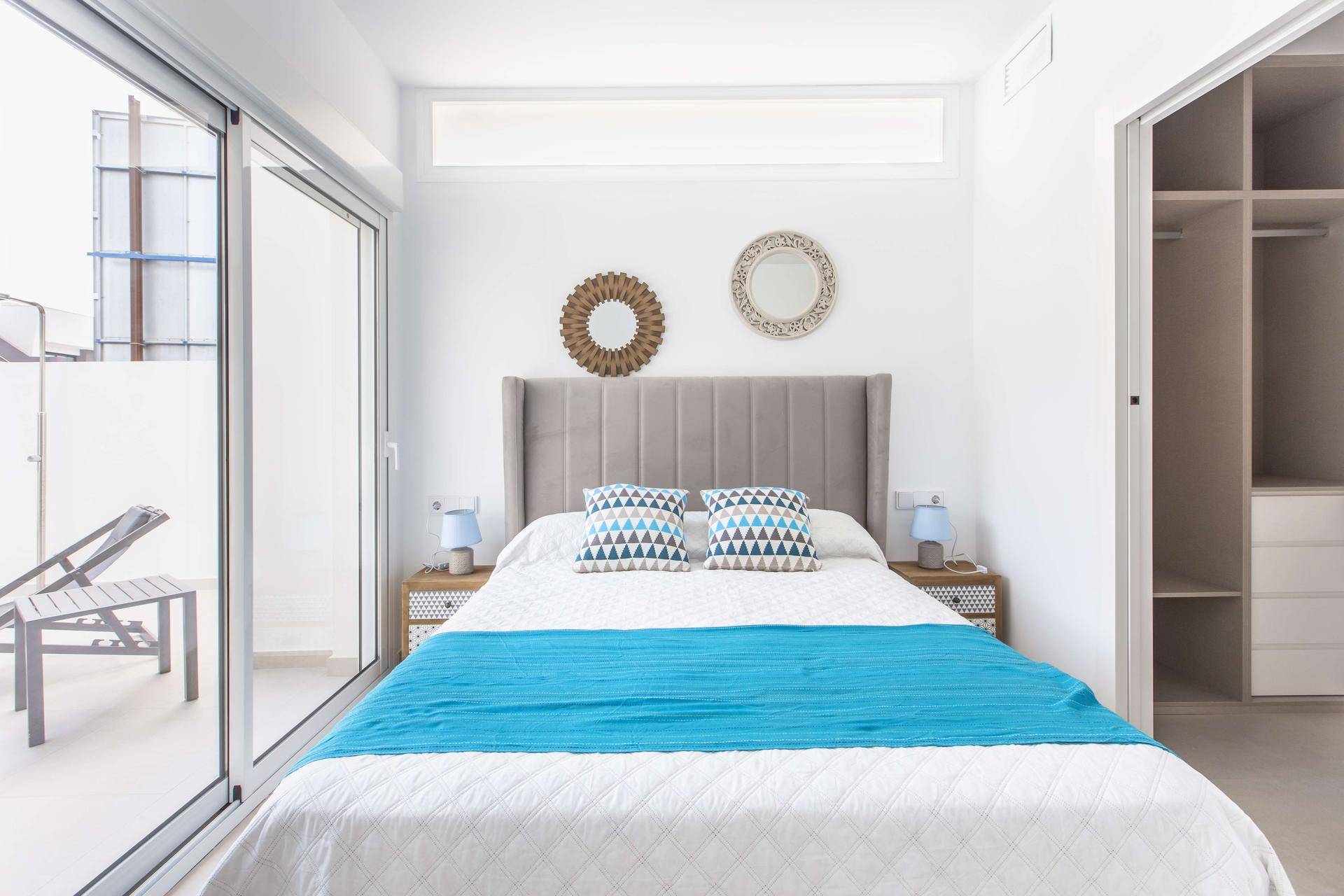 Schlafzimmer mit Zugang zu einer Terrasse, großen Fenstern und integriertem Kleiderschrank.