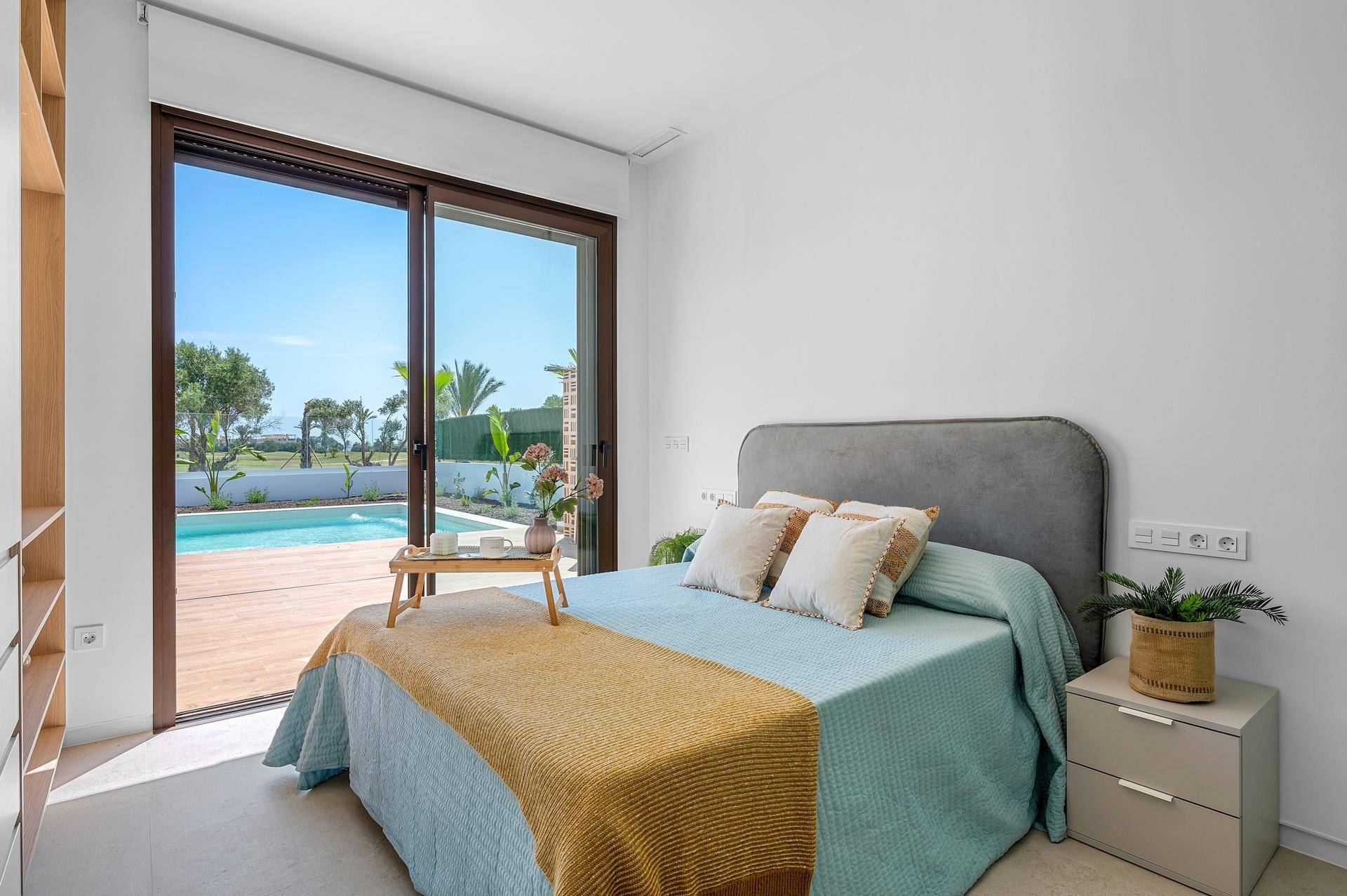Helles Schlafzimmer mit direktem Zugang zum Poolbereich und Panoramablick auf den Golfplatz.