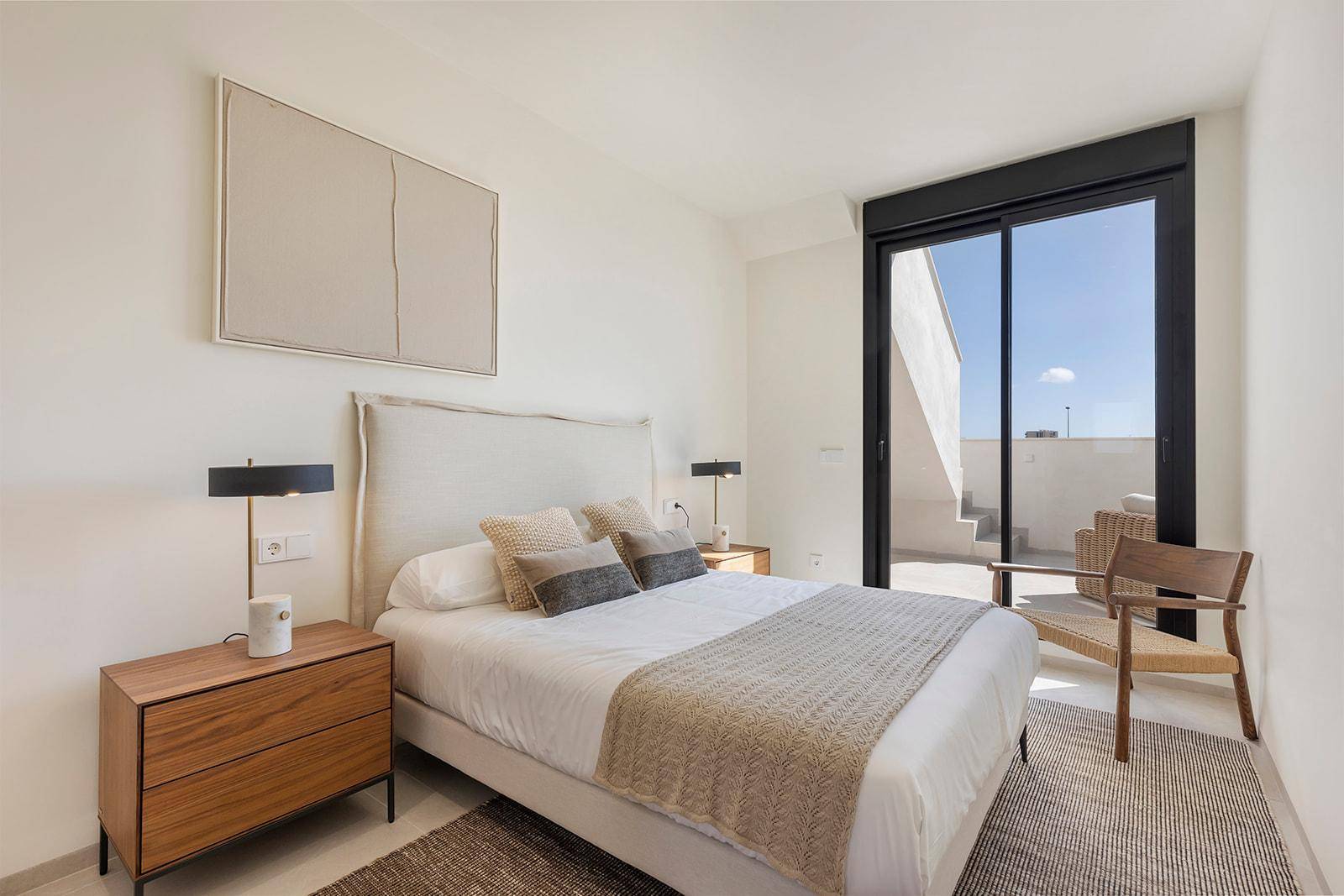 Helles Schlafzimmer mit Zugang zur Dachterrasse, Doppelbett und modernen Möbeln.