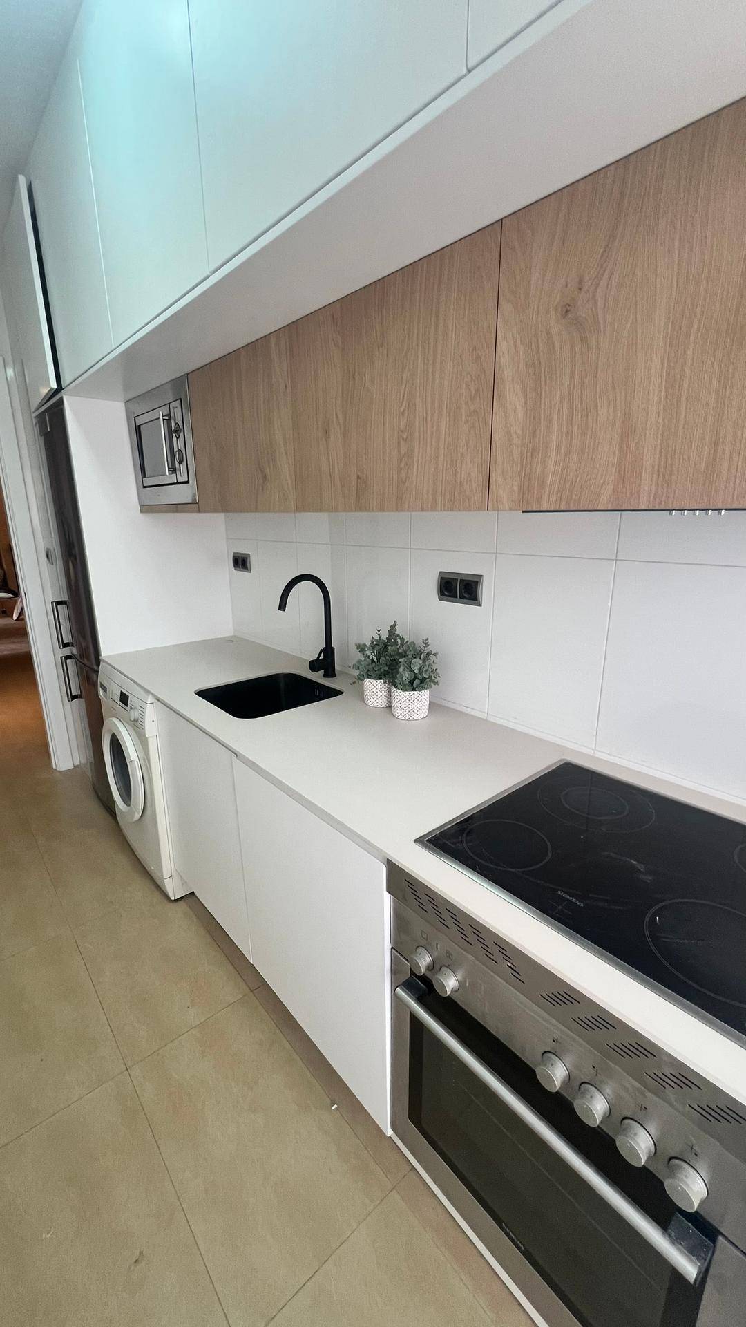 Funktionale Küche mit Induktionskochfeld, Backofen und integrierten Holzschränken.