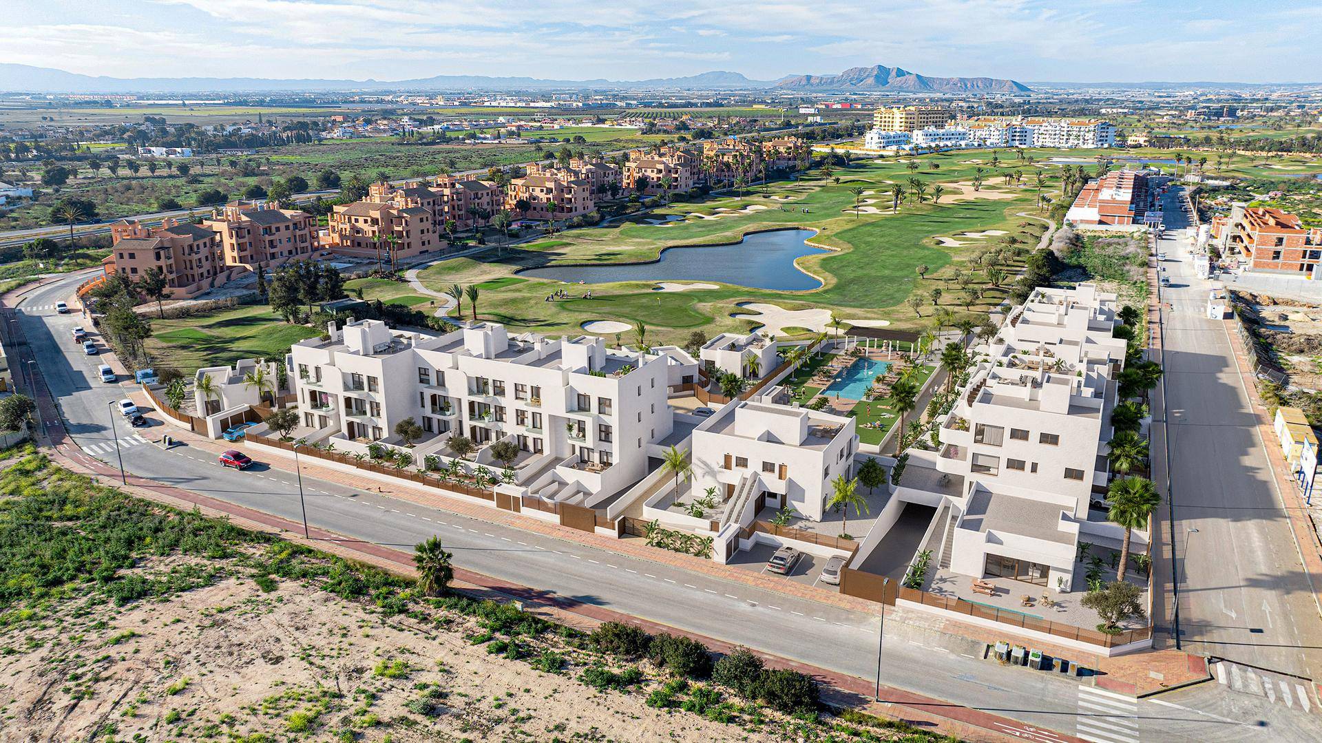 Weitläufige Luftaufnahme der Wohnanlage mit Golfplatz, Seen und der umliegenden Landschaft unter blauem Himmel.