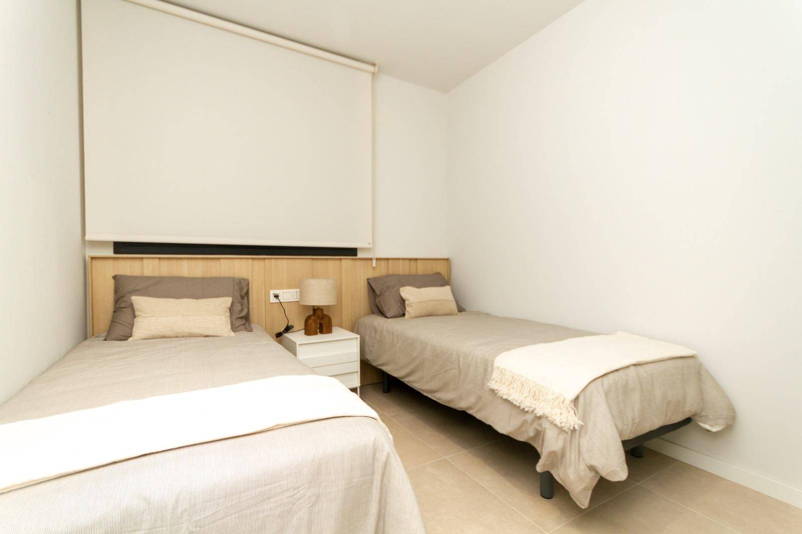 Kinder- oder Gästezimmer mit zwei Einzelbetten, schlichtem Design und Fliesenboden.