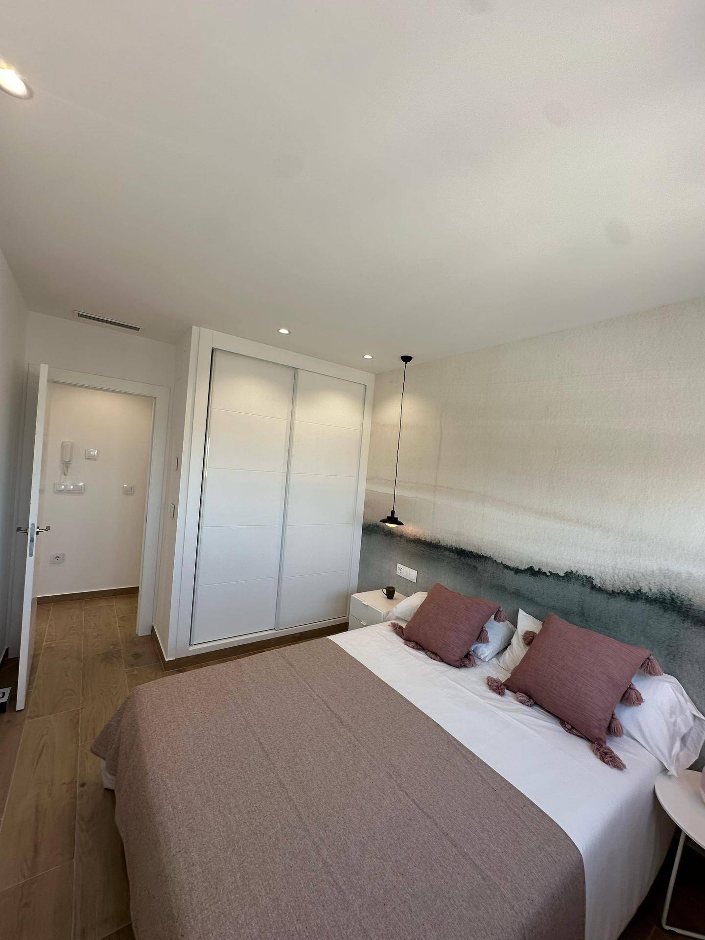Modernes Schlafzimmer mit Doppelbett, Einbauschrank und stilvoller Wandgestaltung.