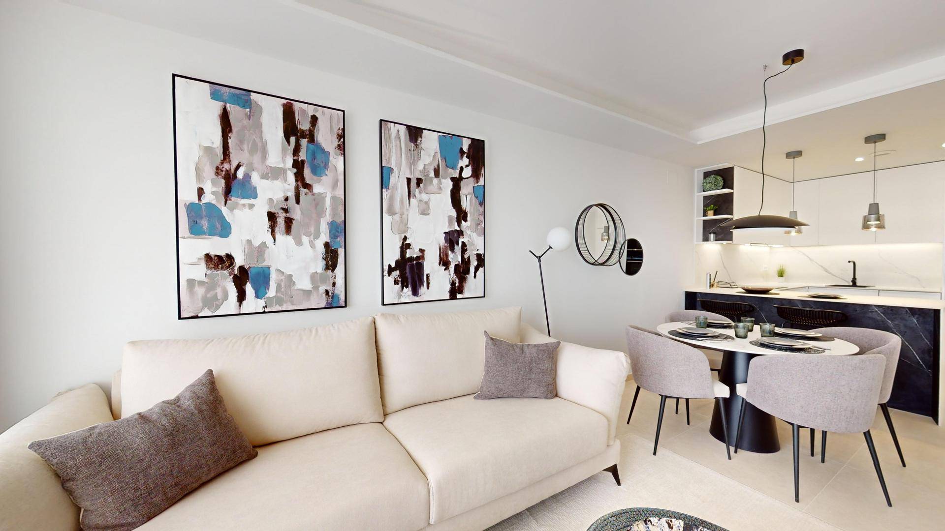 Geräumiger Wohnbereich mit hellem Sofa, Kunstwerken und offener Küche im Hintergrund.