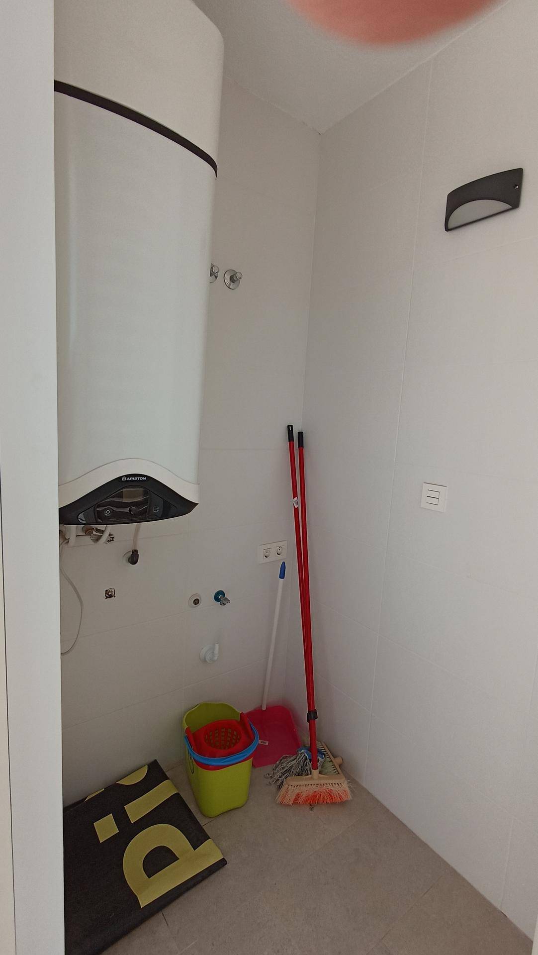 Kleiner Hauswirtschaftsraum mit Warmwasserbereiter und Reinigungsutensilien.