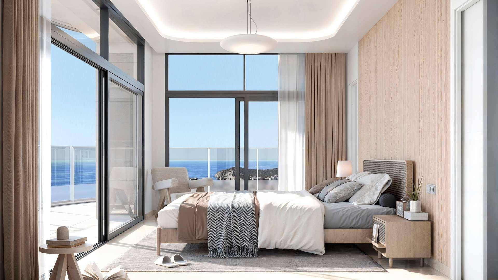 Helles Schlafzimmer mit raumhohen Fenstern, atemberaubendem Meerblick und Balkonzugang.