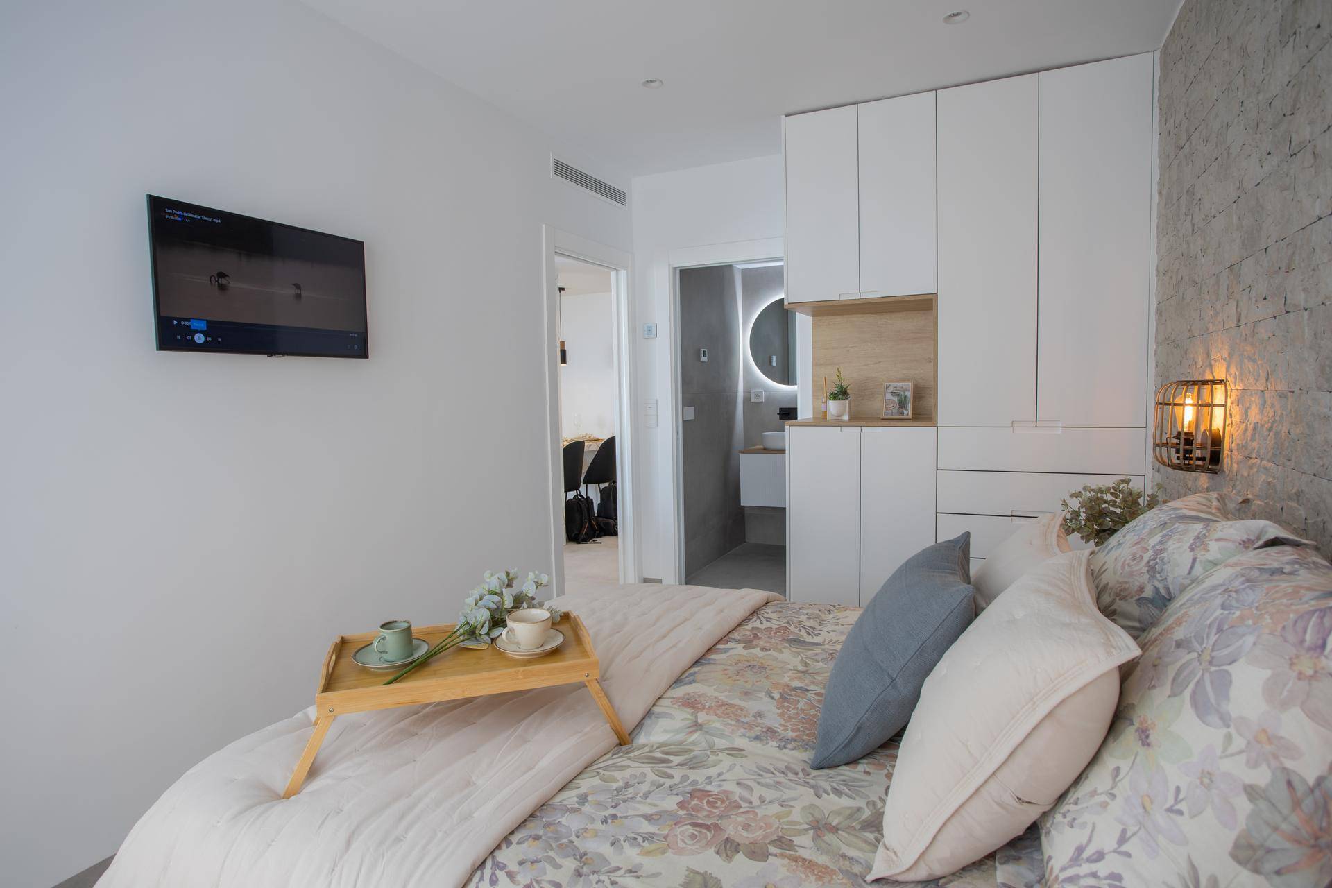 Schlafzimmer mit integrierten Kleiderschränken, Fernseher und direktem Zugang zum Badezimmer.