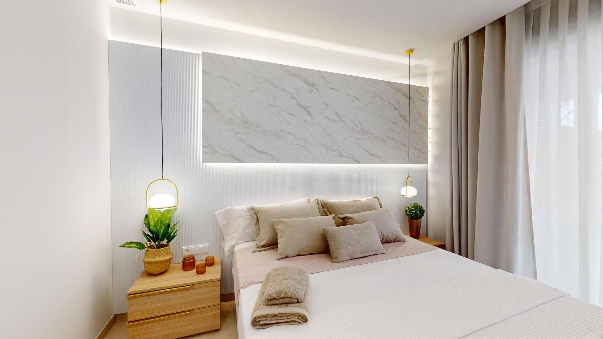 Elegantes Schlafzimmer mit beleuchtetem Marmor-Kopfteil, modernen Nachttischen und hellen Vorhängen am Fenster.