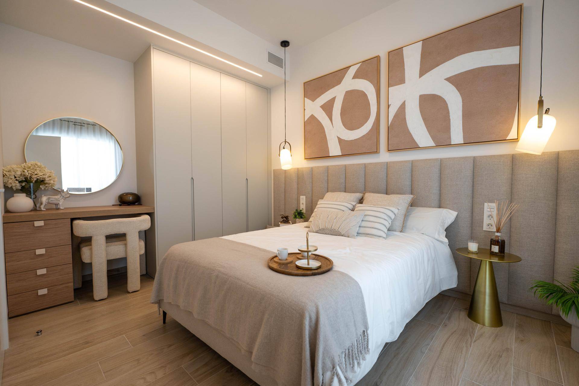 Modernes Schlafzimmer mit beigem Kopfteil, Einbauschränken und Holzboden.