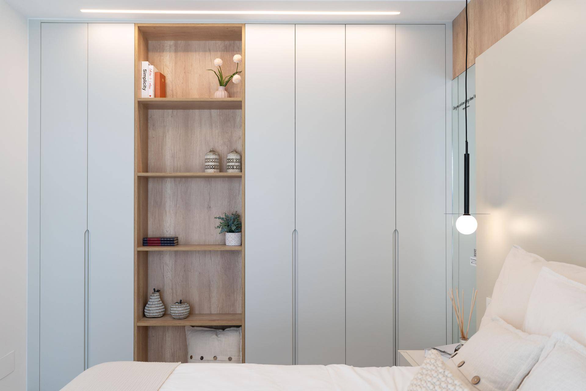 Detailansicht der Einbauschränke mit offenem Regal und stilvoller Dekoration im Schlafzimmer.
