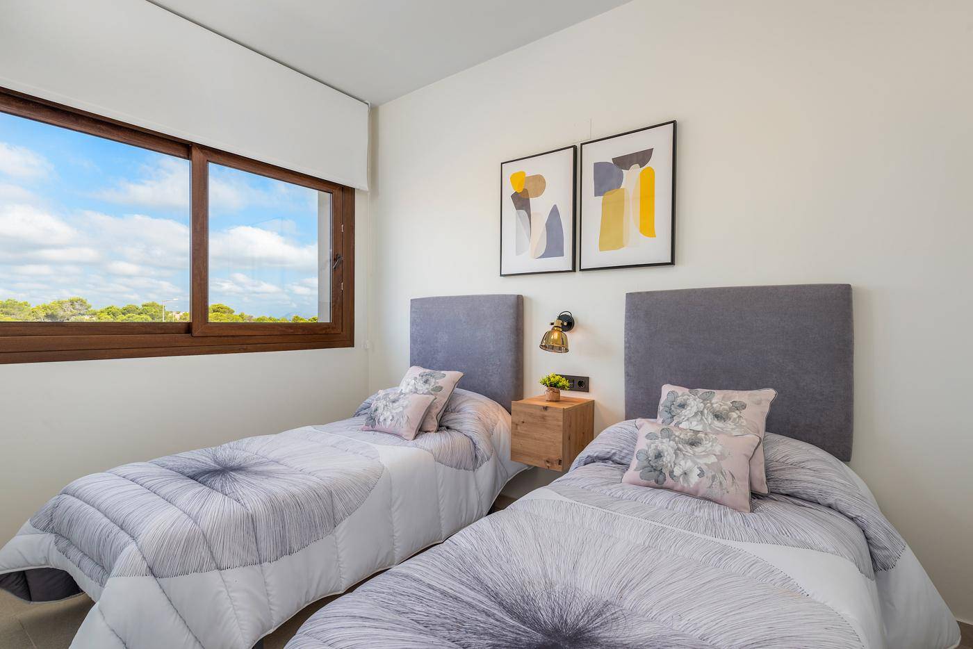 Helles Schlafzimmer mit zwei Einzelbetten, modernen Kopfteilen und einem Fenster mit Landschaftsblick.
