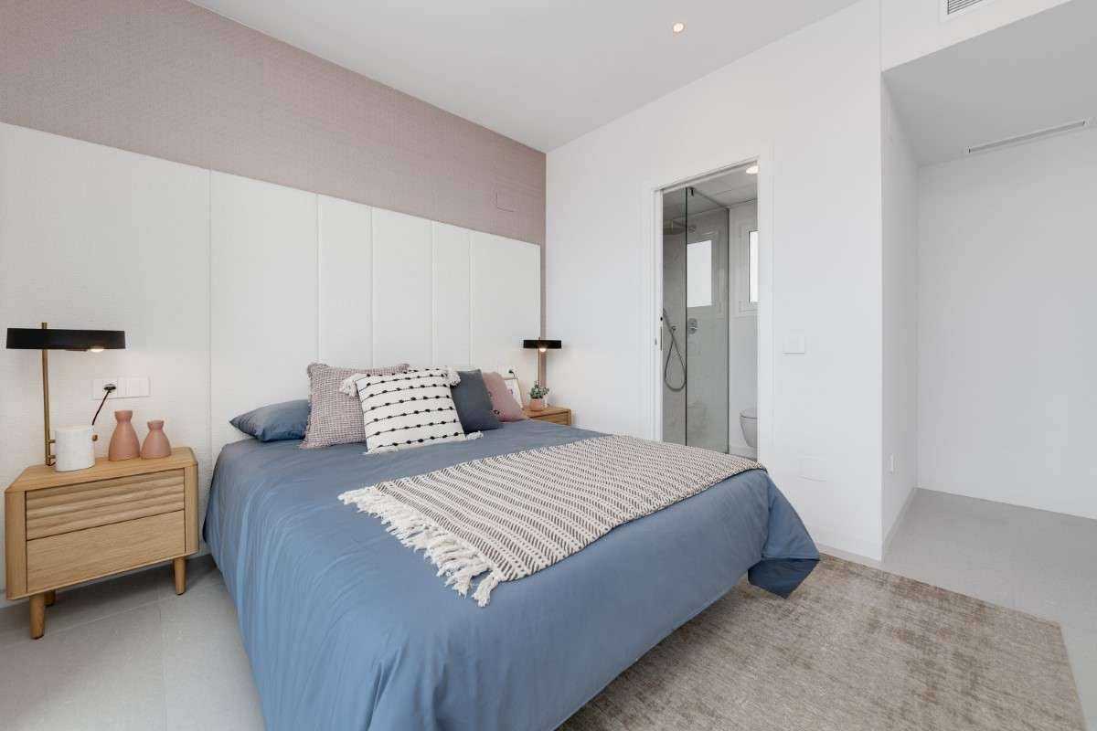 Modernes Schlafzimmer mit großem Bett, Nachttischen und Zugang zu einem angrenzenden Bad.