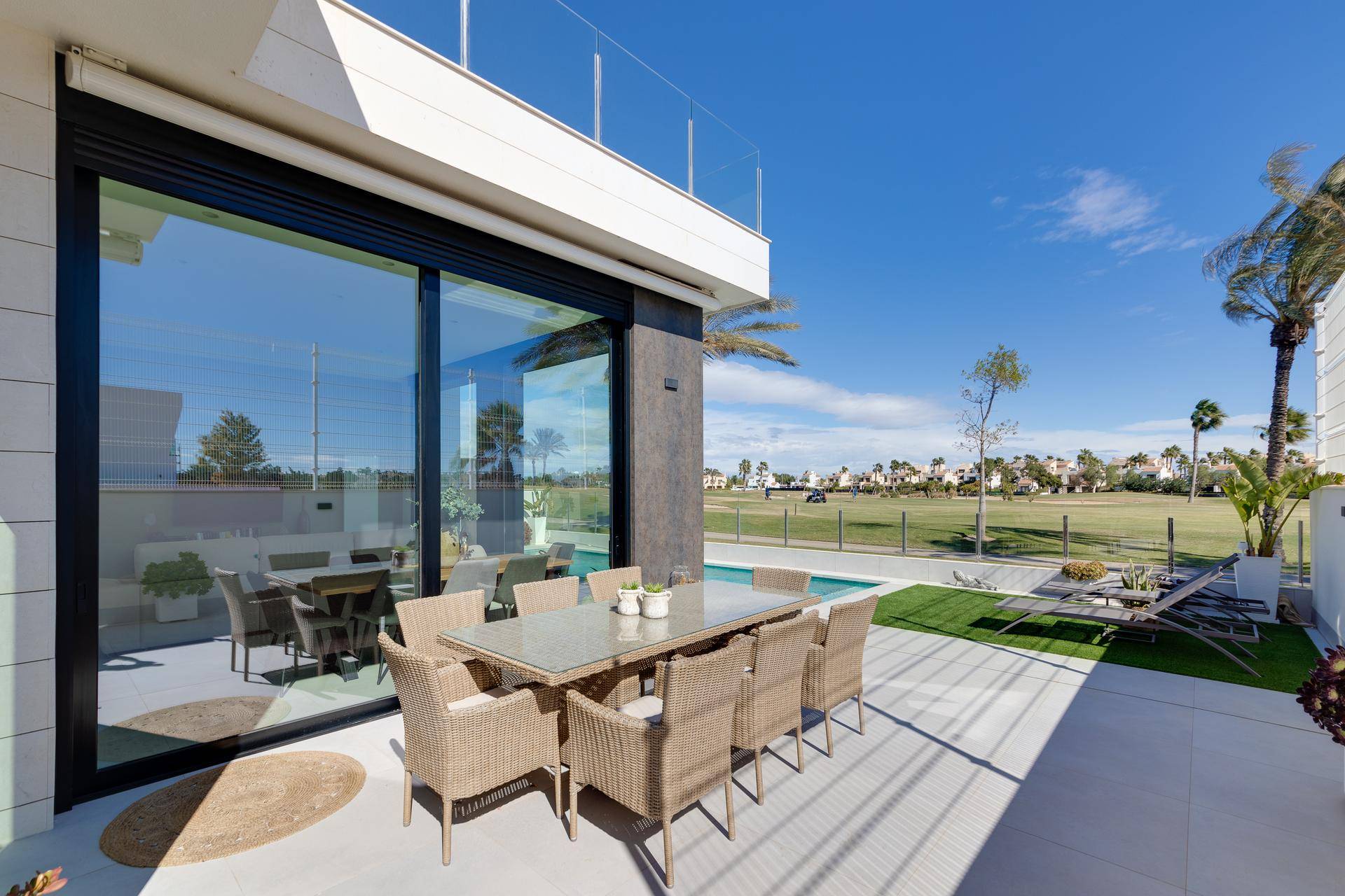 Geräumige Terrasse mit Essbereich und großen Glasfronten, die den Blick auf die grüne Landschaft freigeben.