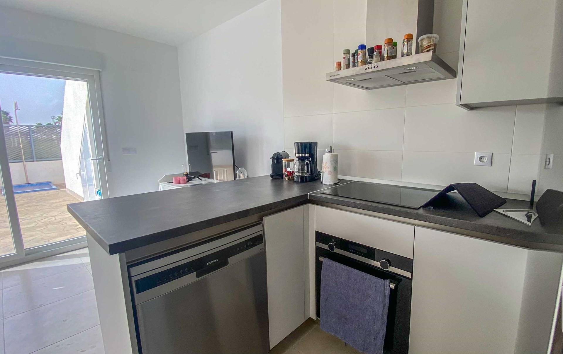 Moderne Einbauküche mit Spülmaschine, Backofen und Kochfeld.
