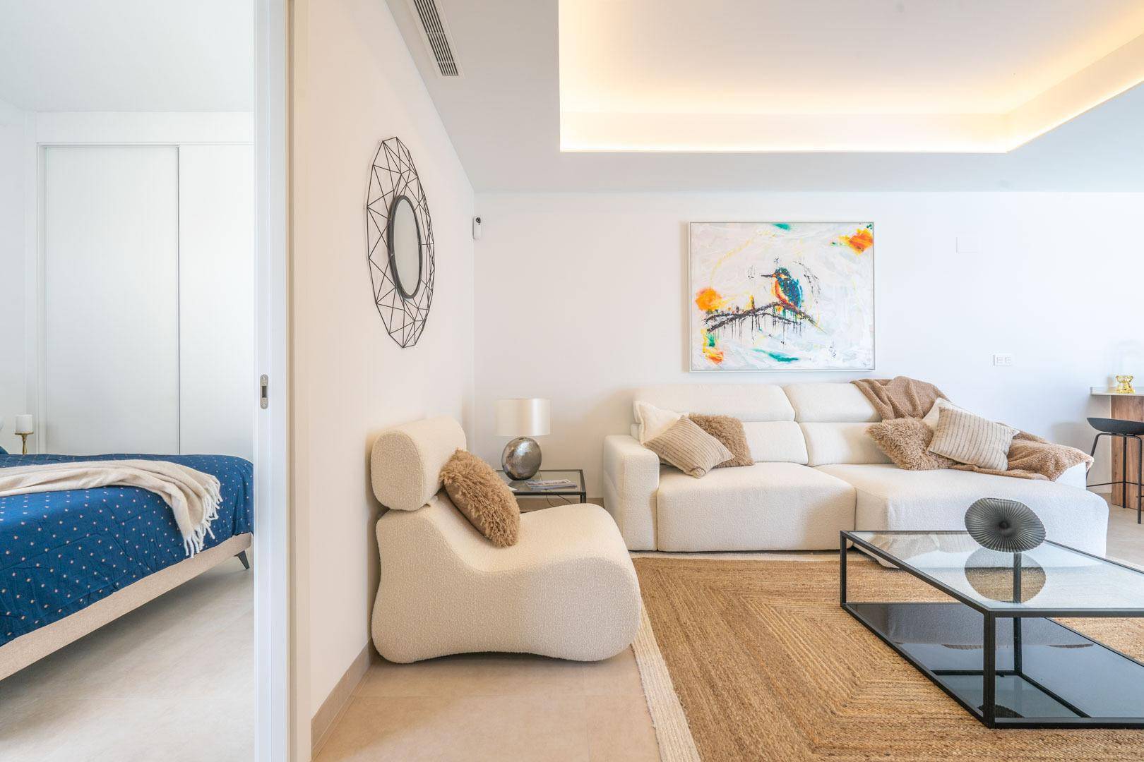 Helles Wohnzimmer mit moderner Einrichtung und Blick auf das angrenzende Schlafzimmer.