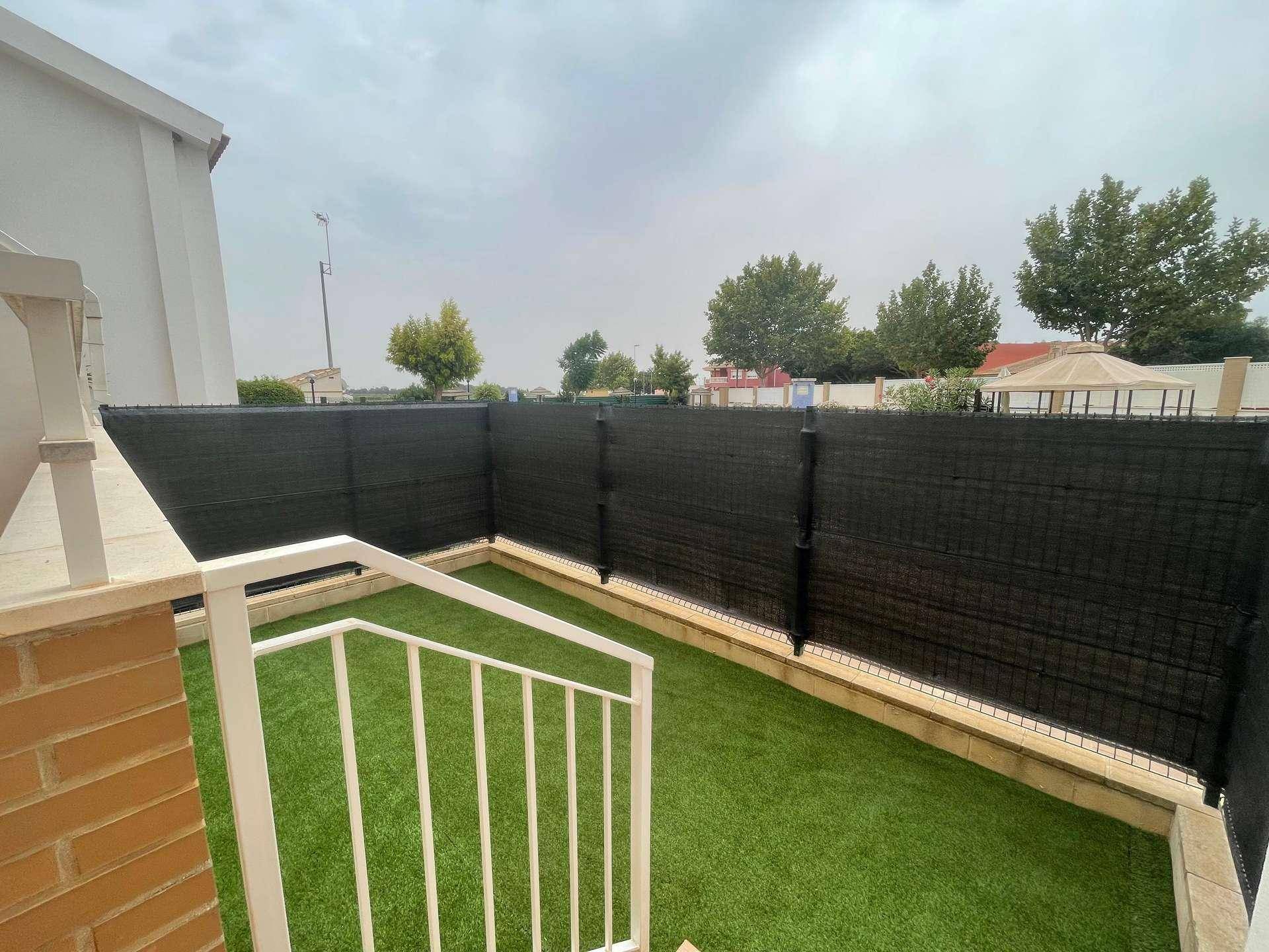 Detailansicht des kleinen, gepflegten Gartenbereichs mit Kunstrasen und Sichtschutz zum Poolbereich.