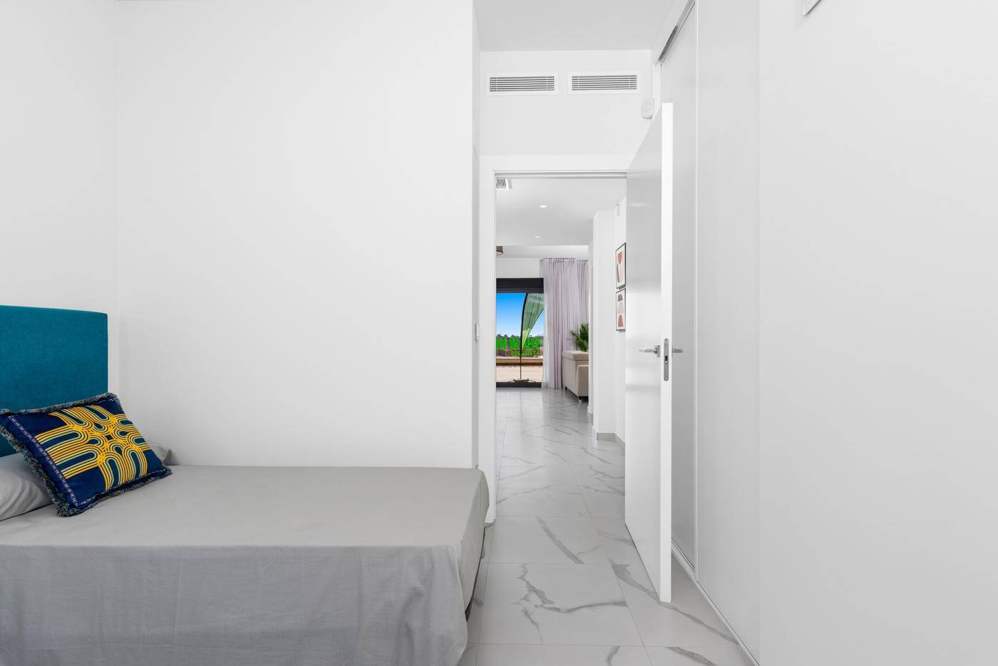 Schlafzimmer mit Zugang zu einem hellen Flur, der zu weiteren Räumen führt.