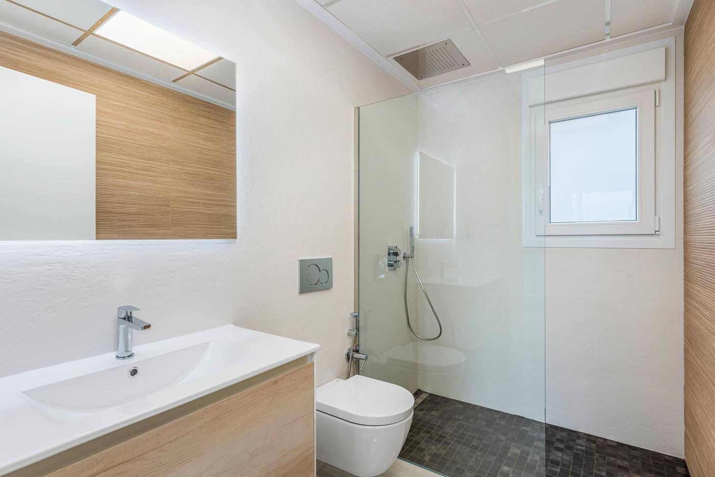 Modernes Badezimmer mit Dusche, wandhängendem WC und Holzverkleidung, ausgestattet mit einem Fenster.