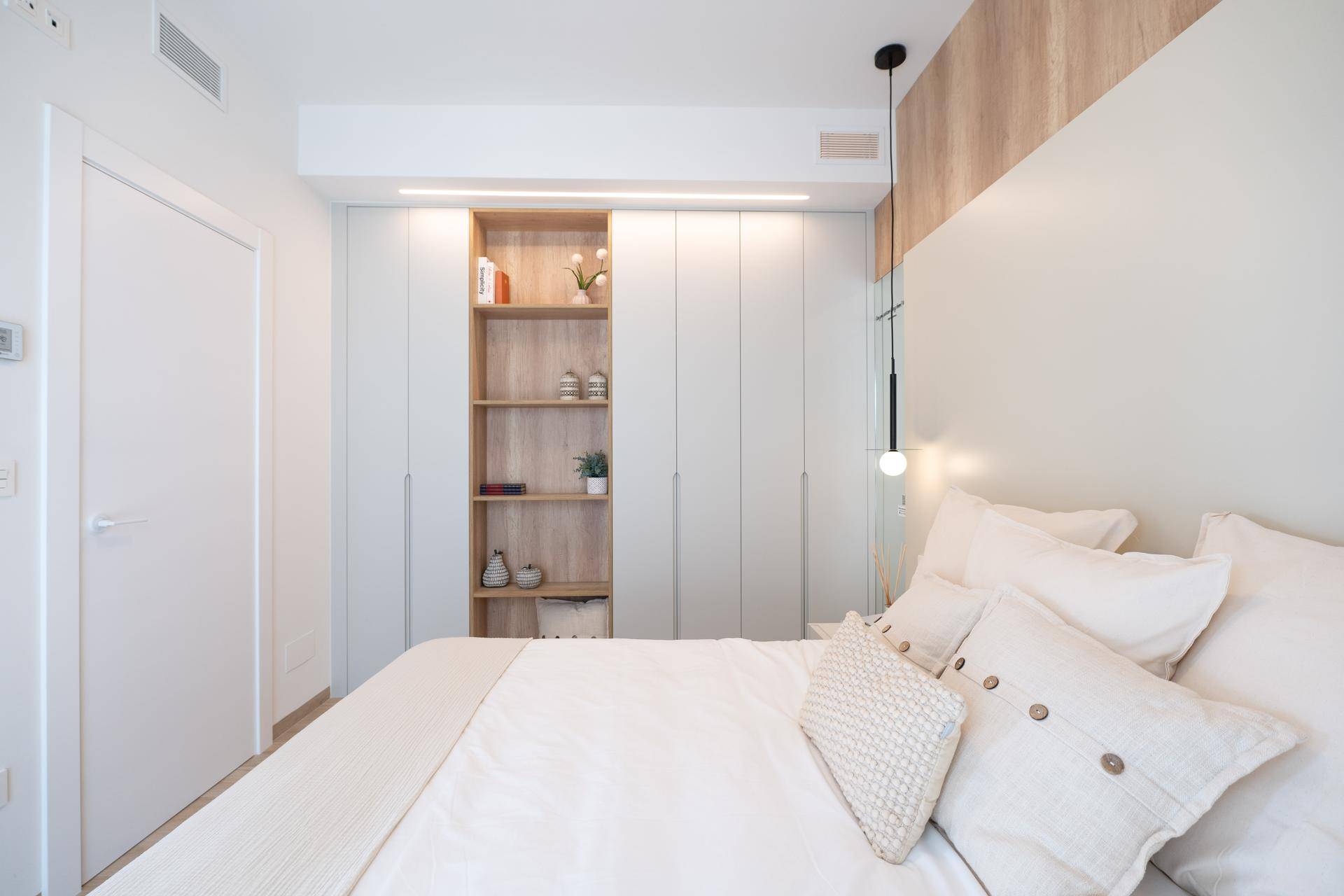 Modernes Schlafzimmer mit Einbauschränken, offenem Regal und hellem Holzboden.