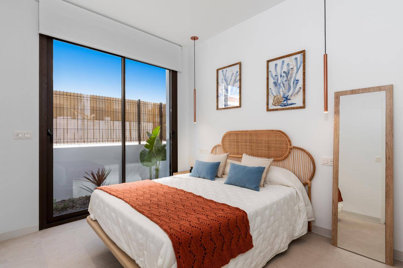 Helles Schlafzimmer mit großen Fenstern und Blick auf den privaten Außenbereich.