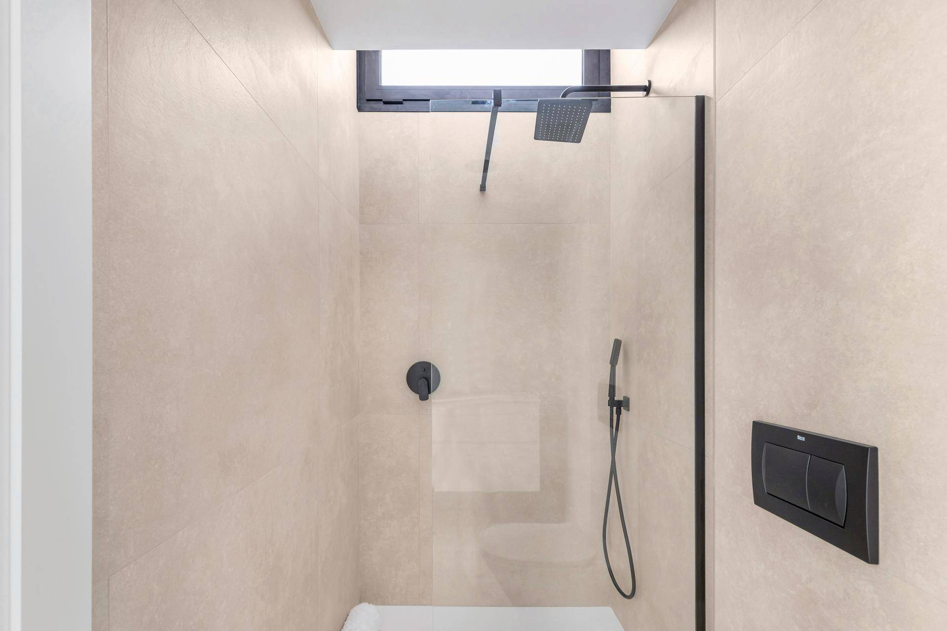 Moderne Dusche mit Regenduschkopf, Glaswand und Fenster für Tageslicht.