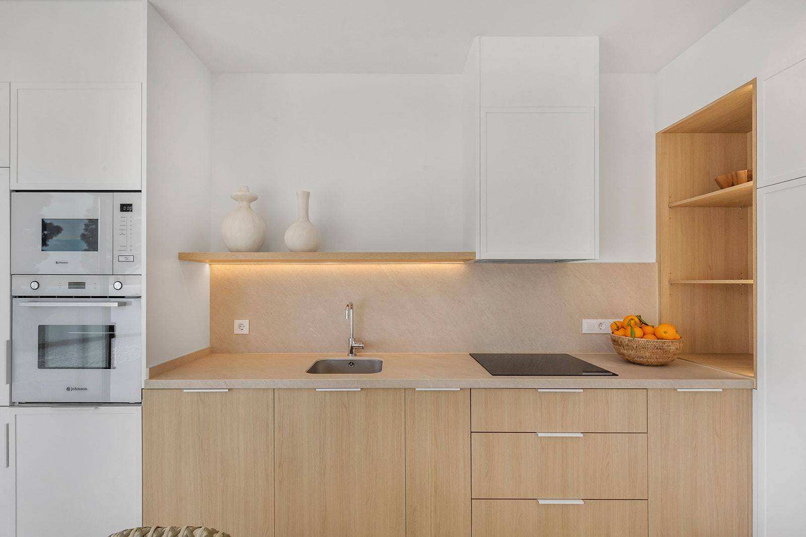 Moderne Einbauküche mit hellen Holzfronten, Induktionskochfeld und integrierten Geräten.