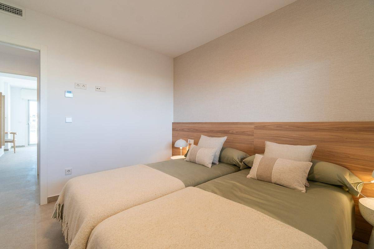 Helles Schlafzimmer mit zwei Einzelbetten, Holz-Kopfteil und schlichter, moderner Einrichtung.