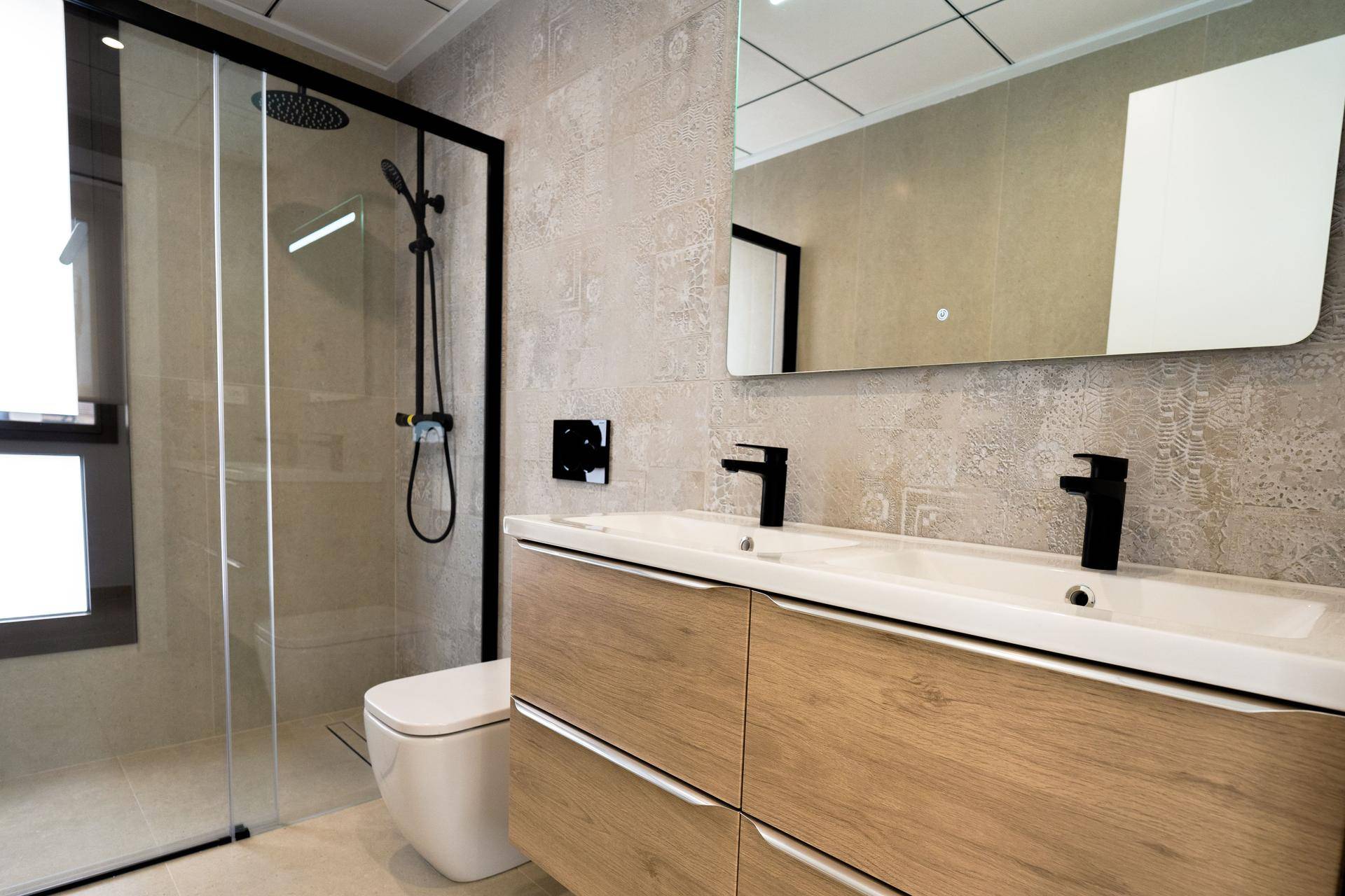 Modernes Badezimmer mit Doppelwaschbecken, begehbarer Dusche und stilvollen Fliesen.