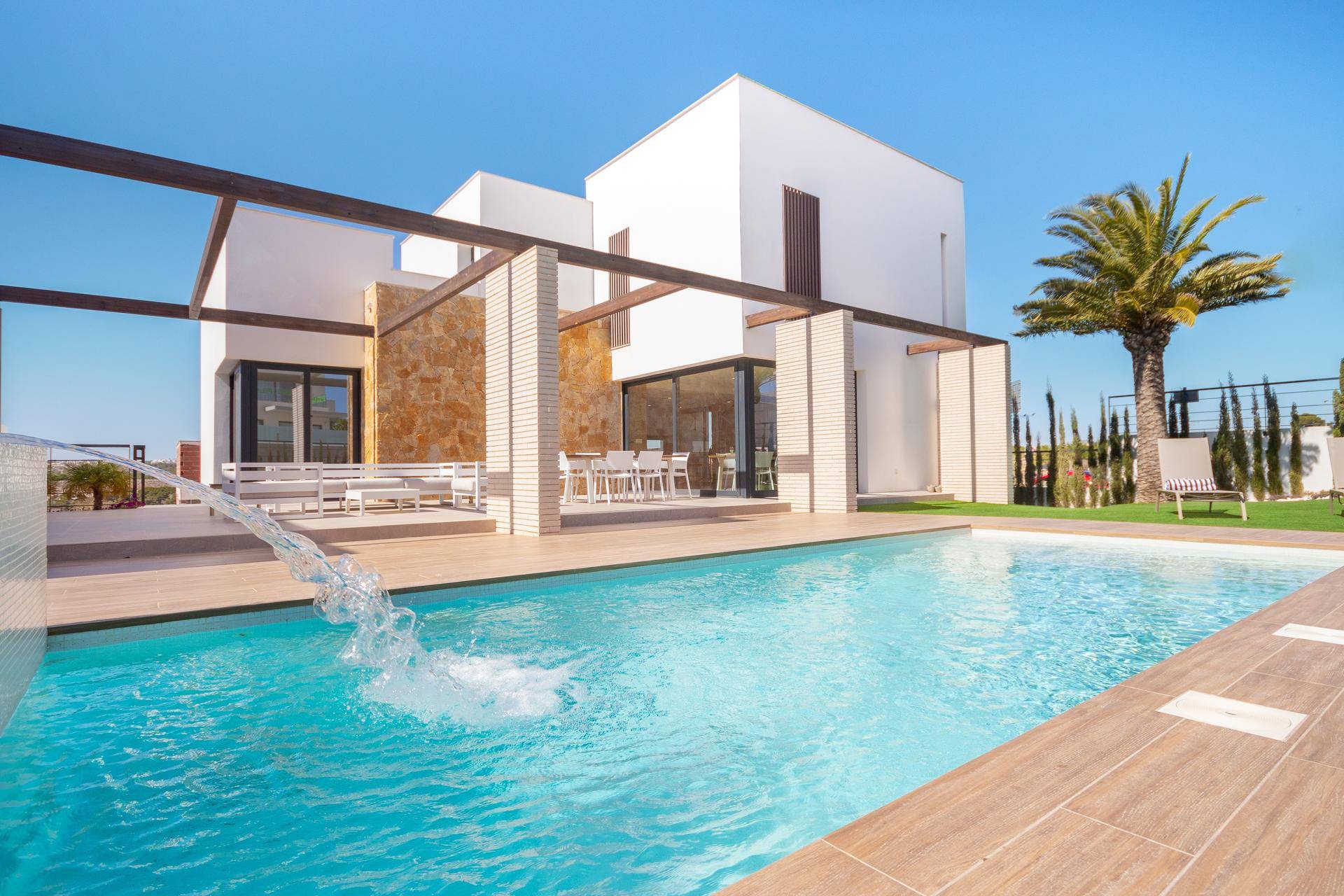 Luxuriöse Außenanlage mit großem Swimmingpool, Holzdeck und stilvollen Möbeln für entspannte Stunden.