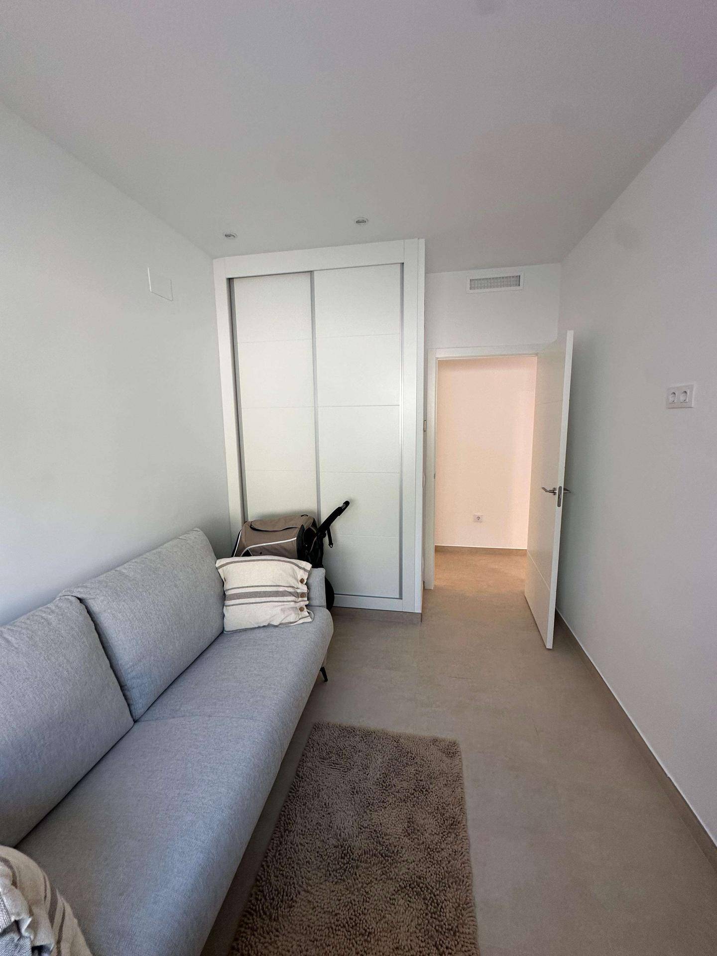 Kleiner Raum mit Sofa und Schiebetürenschrank, ideal als Gästezimmer oder Arbeitszimmer.