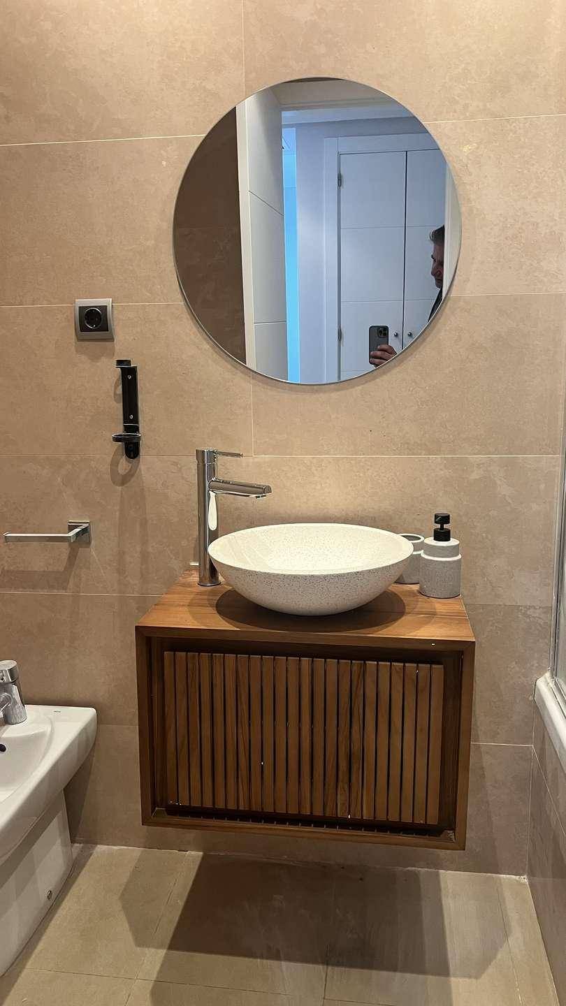 Modernes Badezimmer mit Aufsatzwaschbecken auf Holzunterschrank, rundem Spiegel und Bidet.