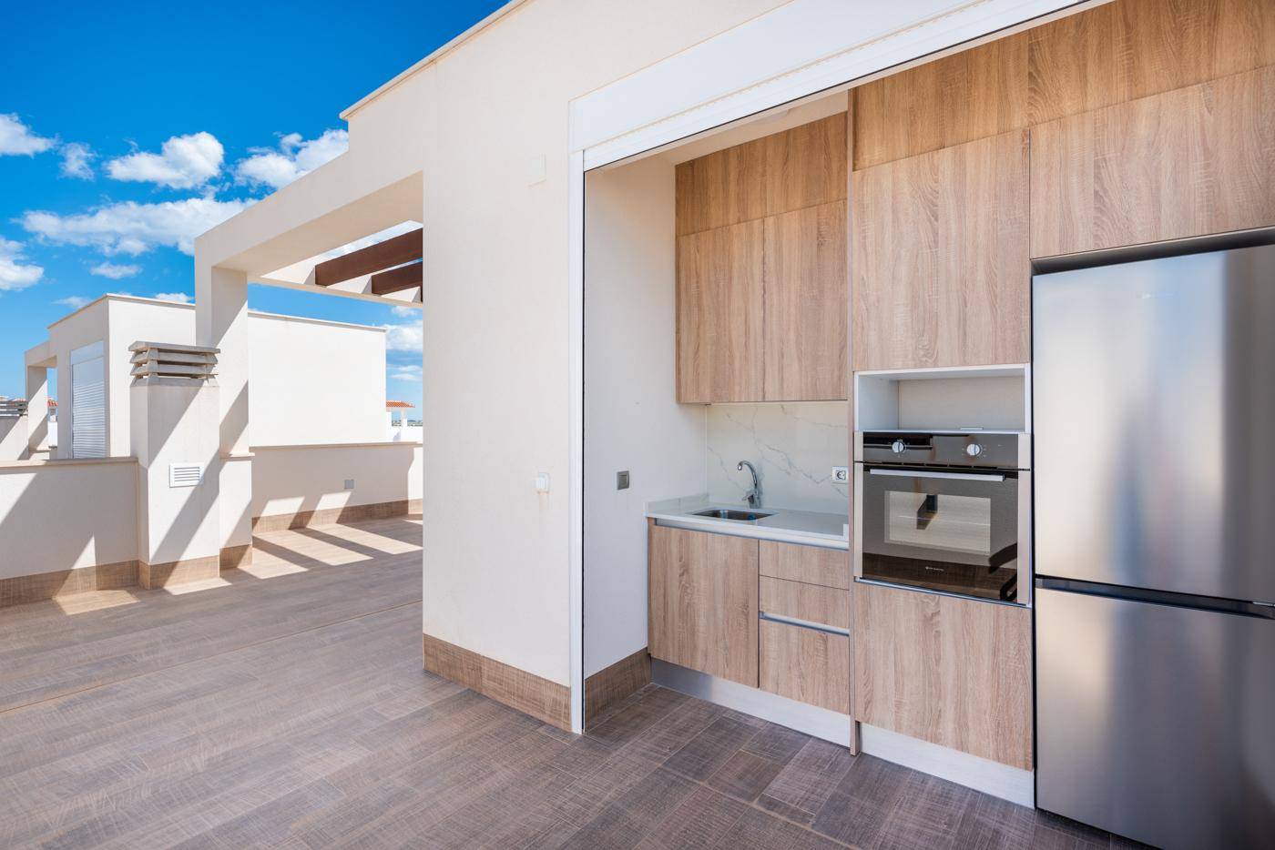 Praktische Außenküche auf der Terrasse mit Kühlschrank und Backofen, perfekt für gesellige Abende.