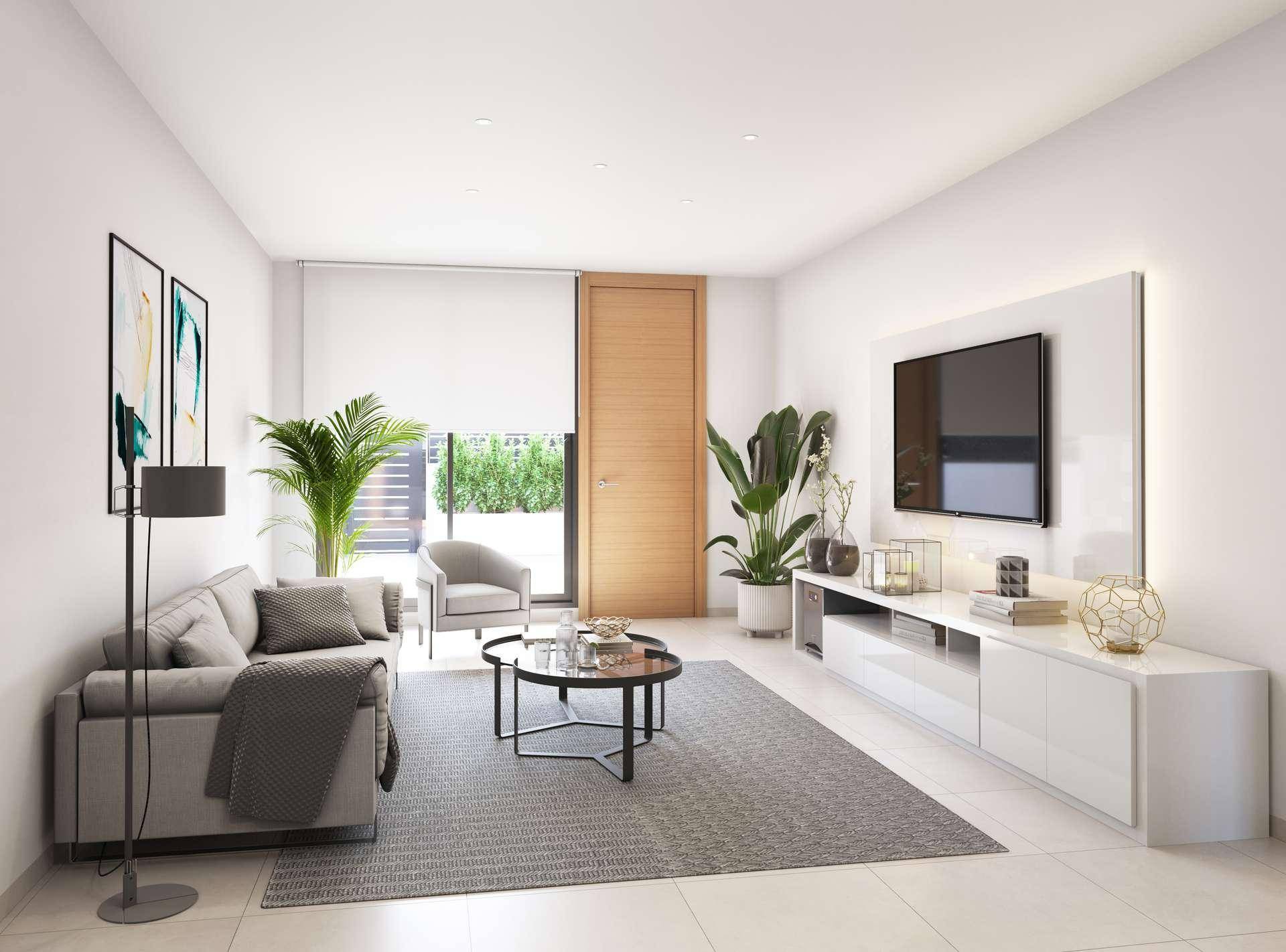 Modernes Wohnzimmer mit beigem Sofa, Fernseher und Zugang zu einem grünen Außenbereich.