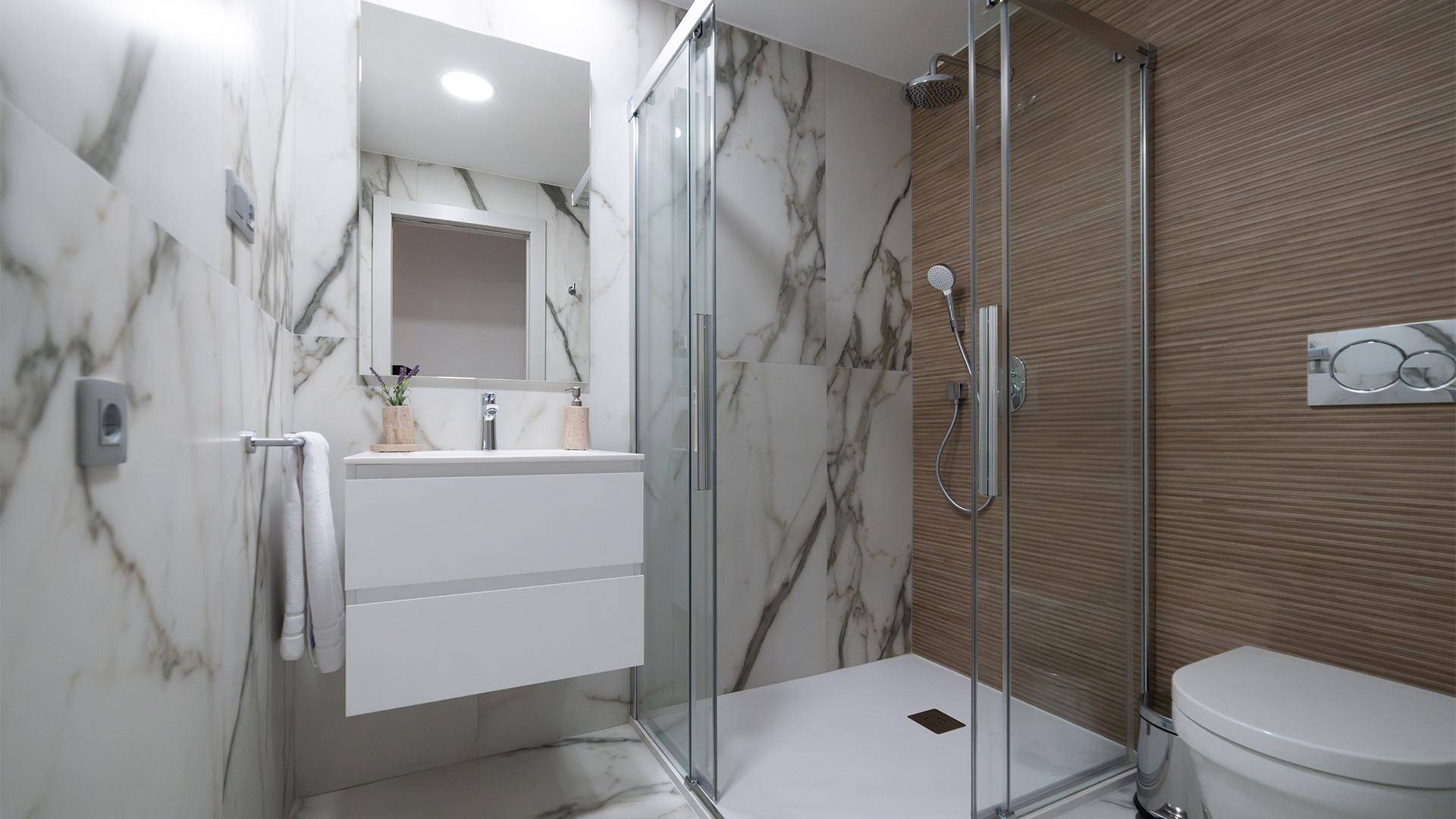 Modernes Badezimmer mit begehbarer Dusche, Marmorfliesen und eleganten Armaturen.