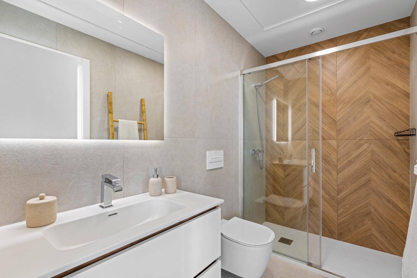 Elegantes Badezimmer mit Dusche, modernem Waschtisch und beleuchtetem Spiegel.